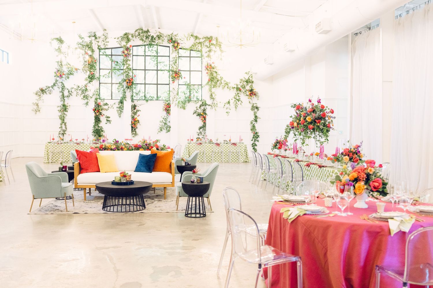Wedding reception space featuring pink tablecloths and hanging floral arrangements.