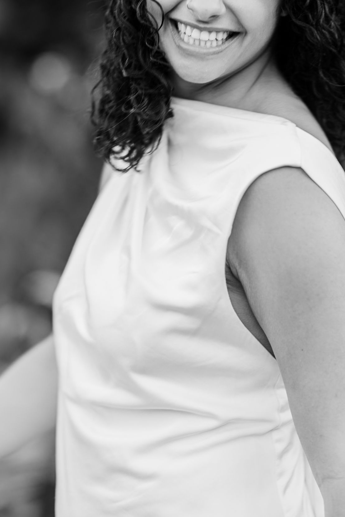 A series of black and white portrait photos showing someone in a white sleeveless top with curly hair and bright smile.
