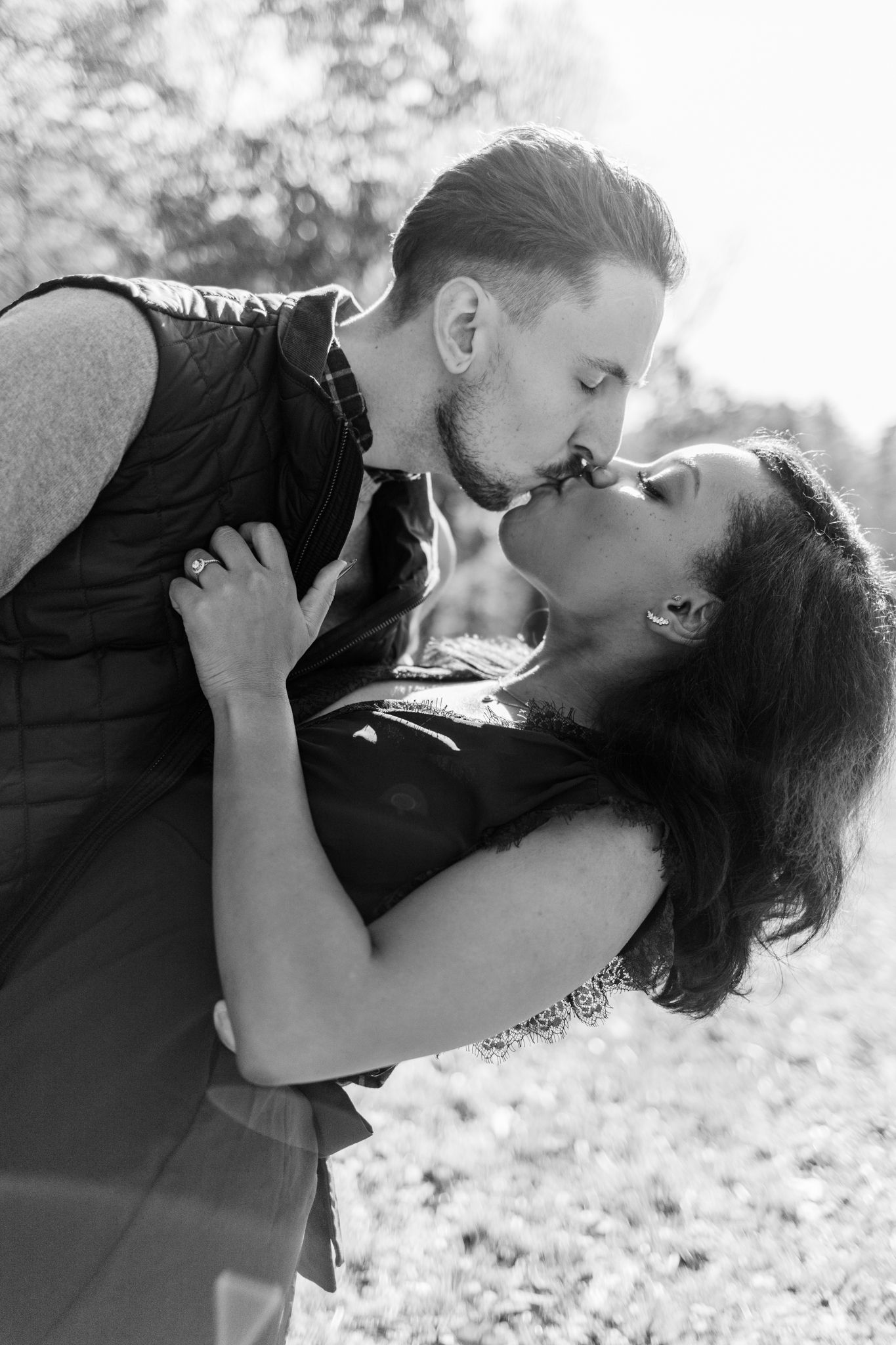 A romantic black and white photo sequence showing a couple sharing tender kisses while lying in grass outdoors.
