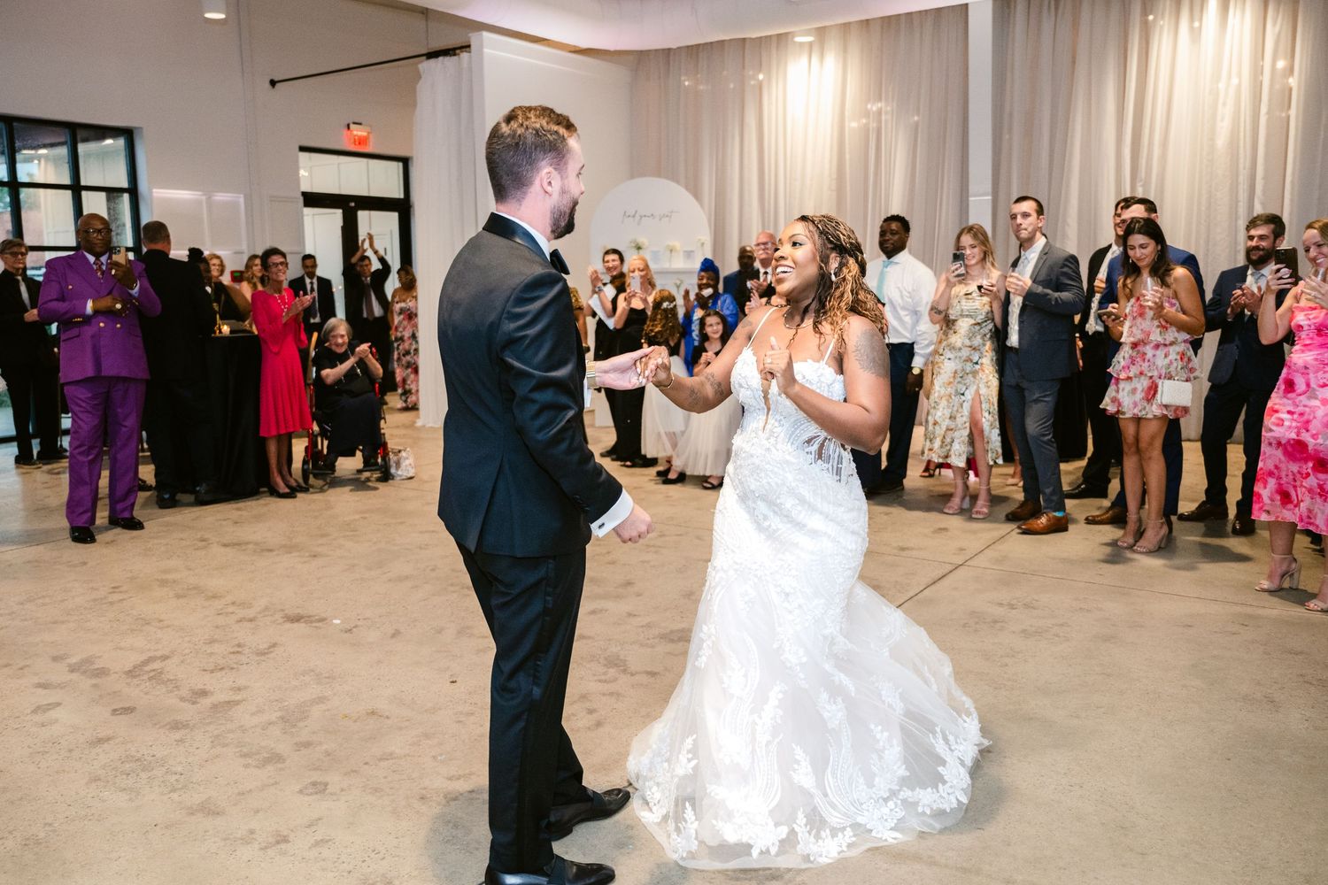 Couples dancing together at an elegant wedding reception in a modern venue with white decor.