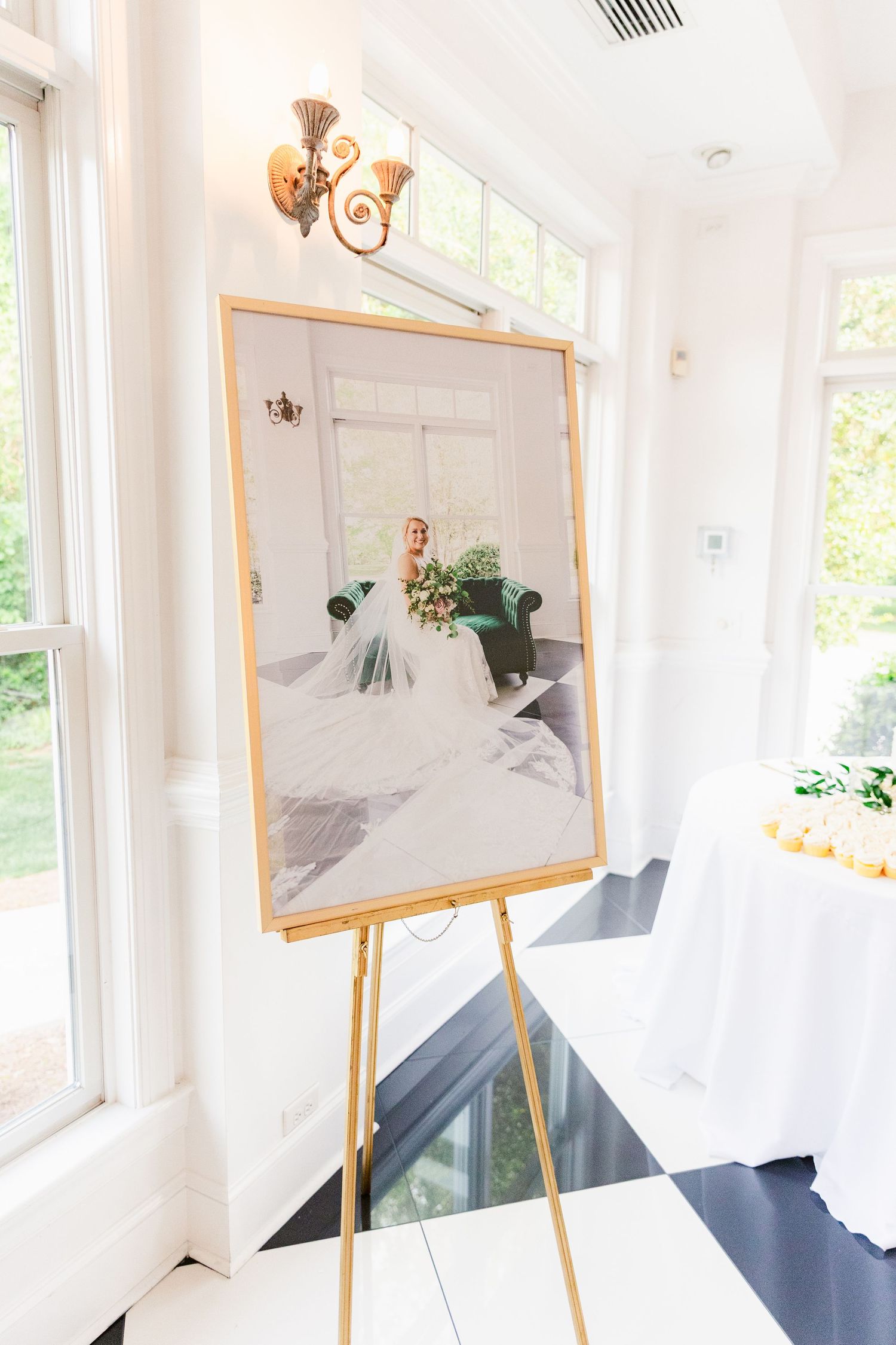Art display setup with wooden easels showing framed artwork in a bright white room with natural lighting.