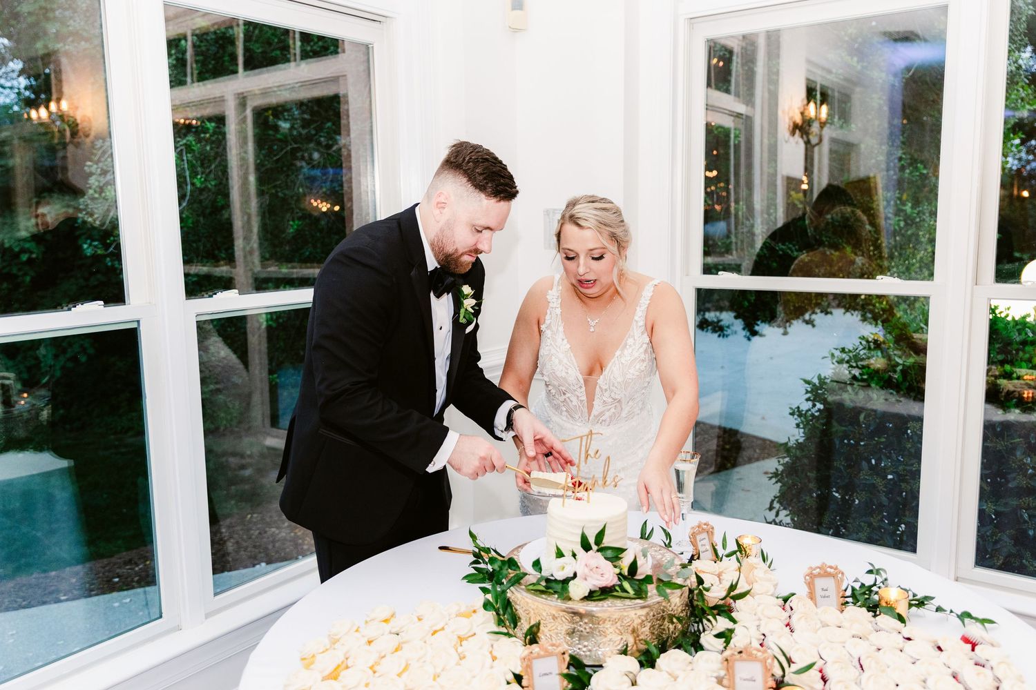 A couple signs their wedding documents at an elegant white conservatory venue with natural lighting.