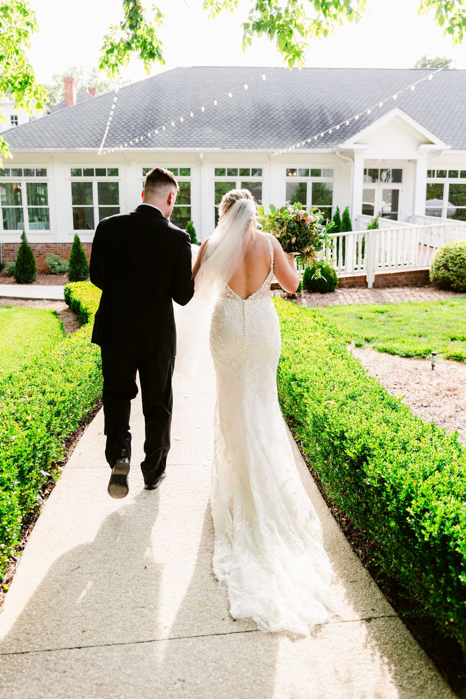 A couple in wedding attire walks along a garden path in a series of romantic shots showing their movement away from camera.