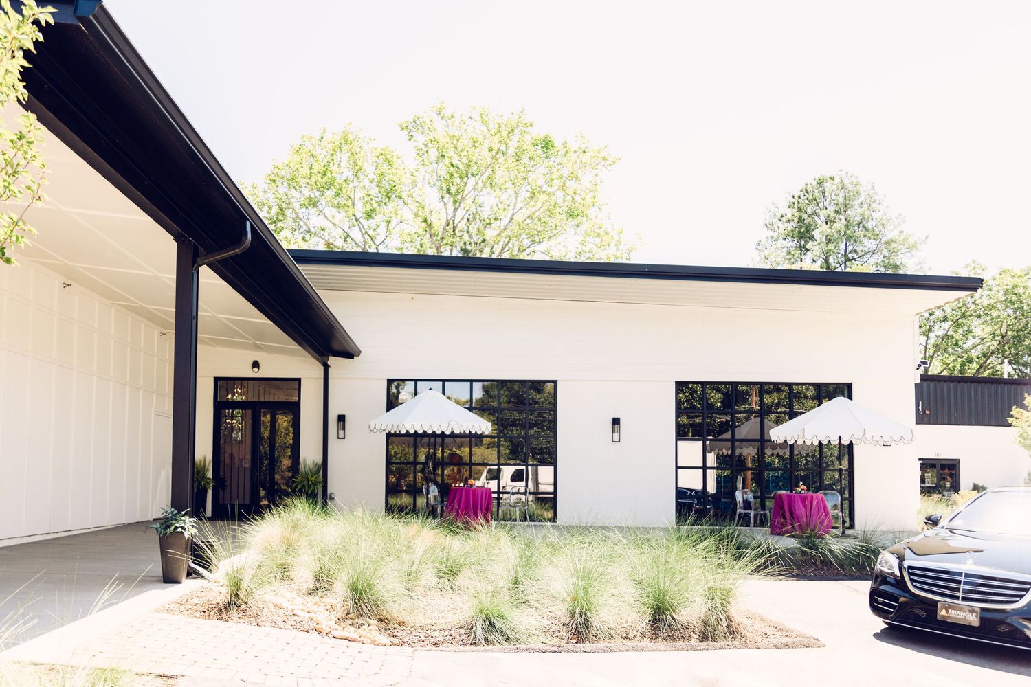 Modern white single-story commercial building with black trim and landscaping along a curved driveway.