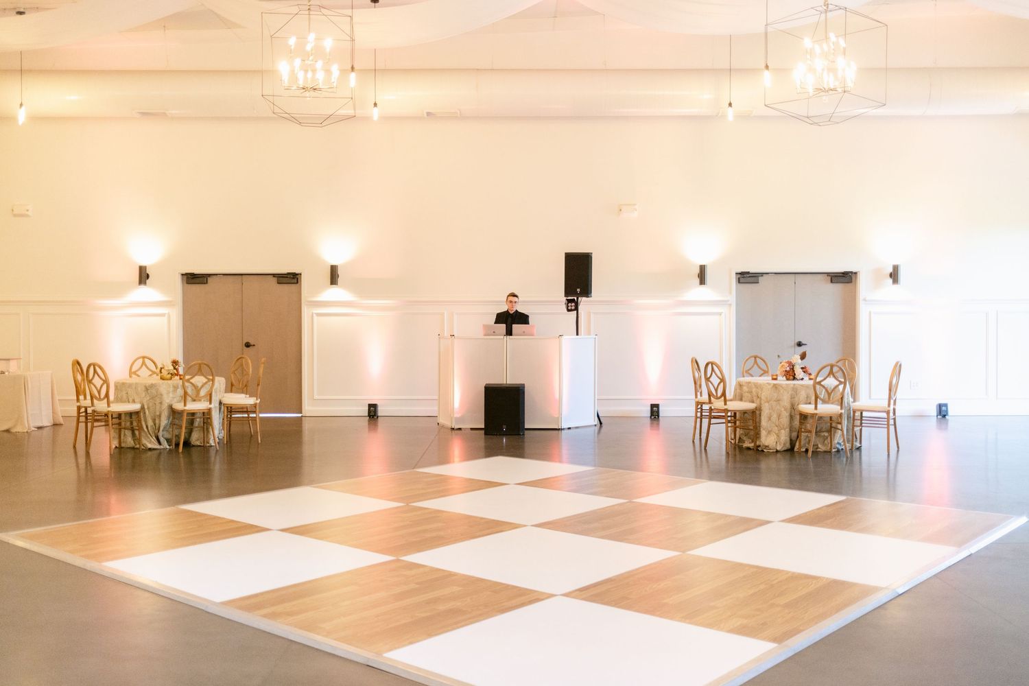 Large open event space with polished floors and white walls showcasing different room layouts and seating arrangements.