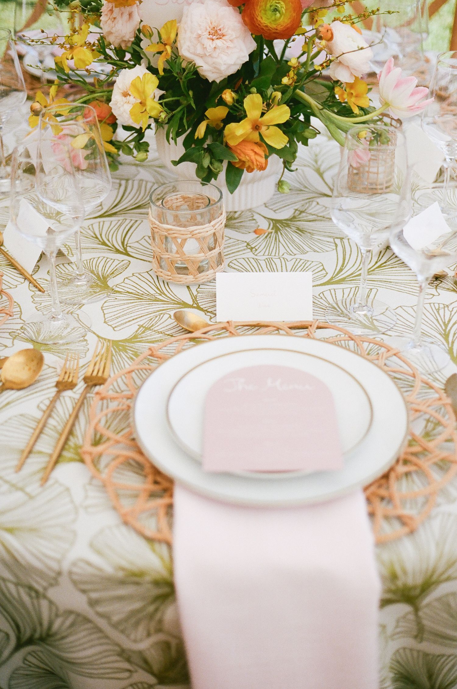 Elegant wedding table setting with floral centerpieces, gold accents, and patterned linens.