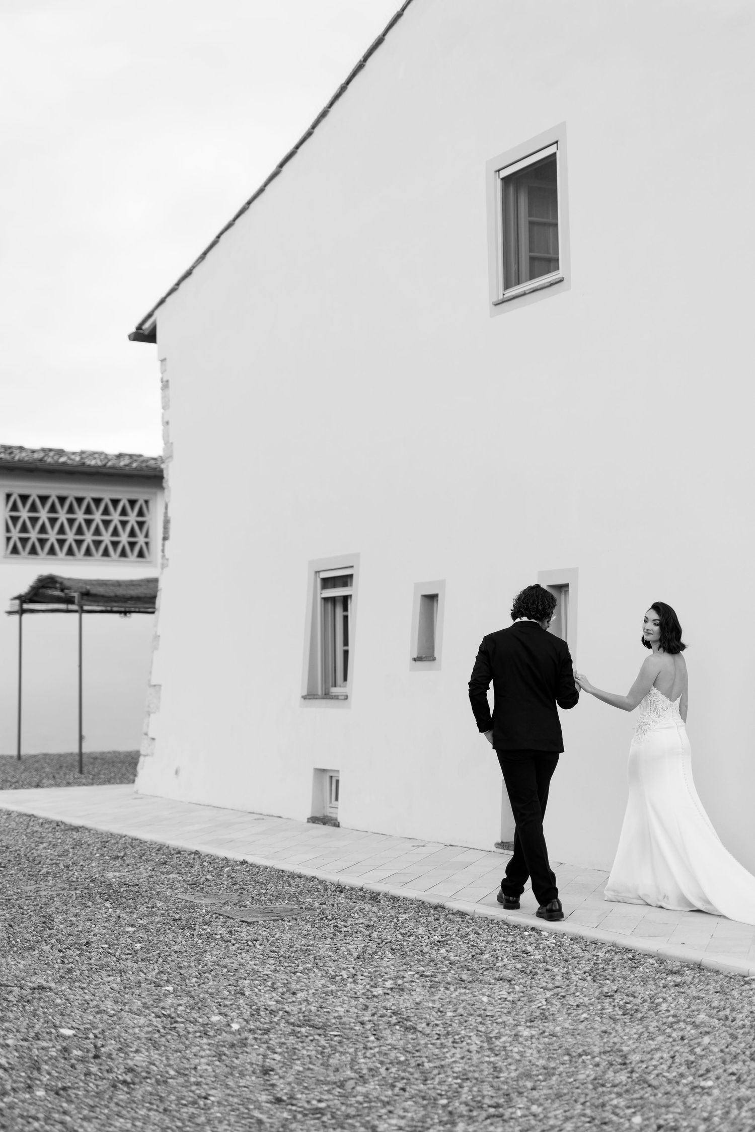 Minimalist black and white wedding photography sequence against stark white building exterior.