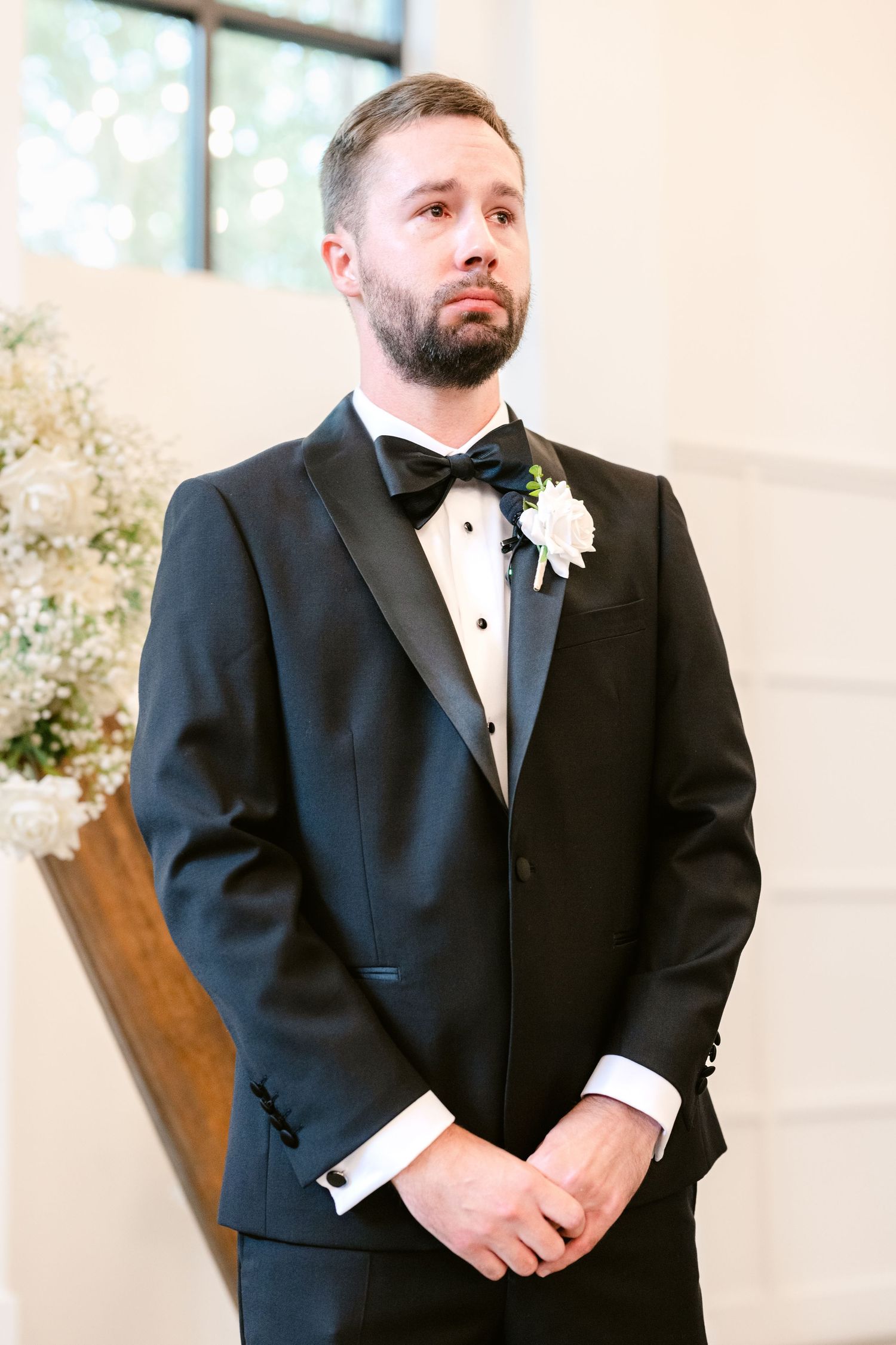 Four elegant wedding portraits showing a groom in a classic black tuxedo with white boutonniere against a light background.