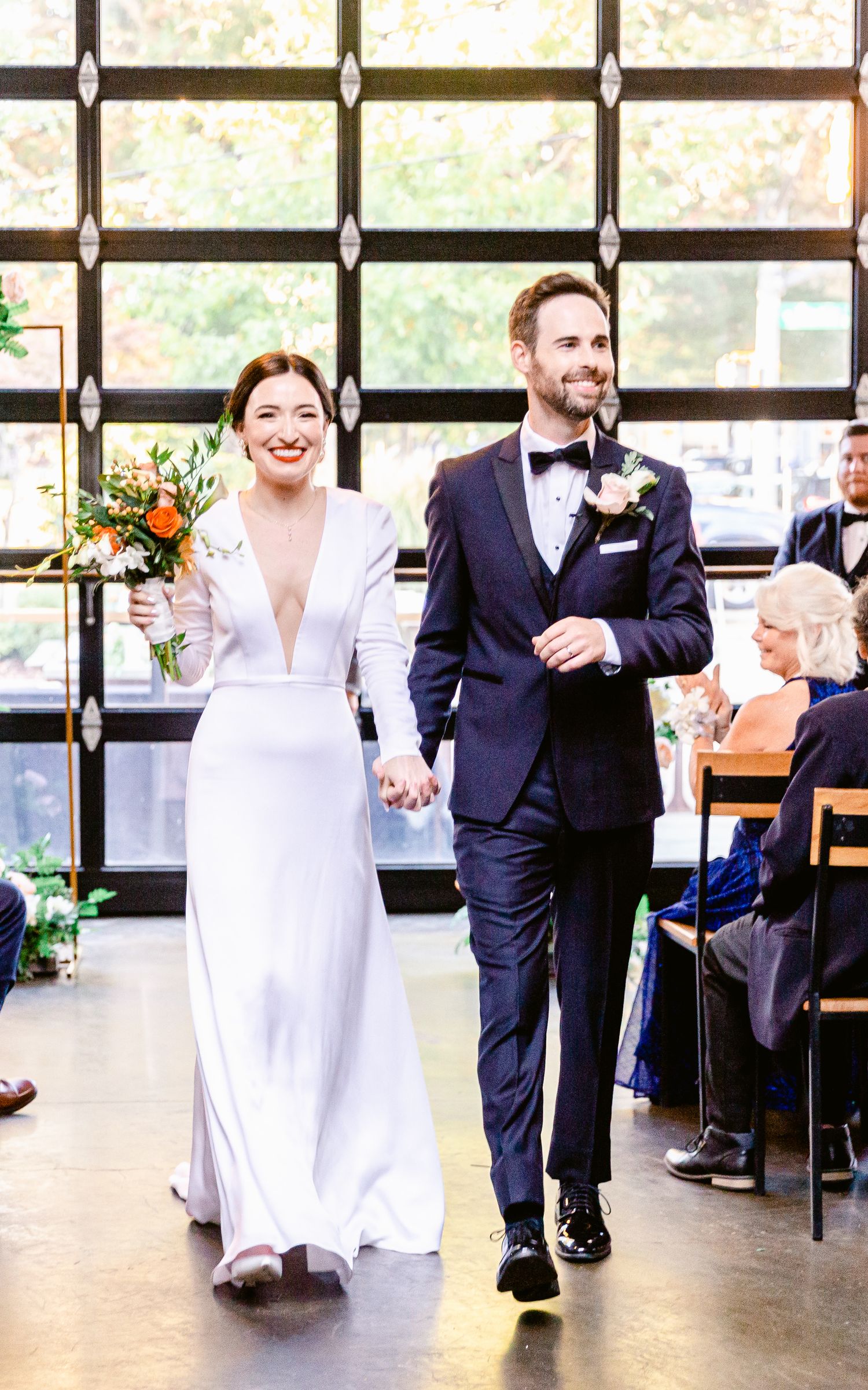 A couple performs a romantic dance move during their first dance at a wedding reception in a bright windowed venue.