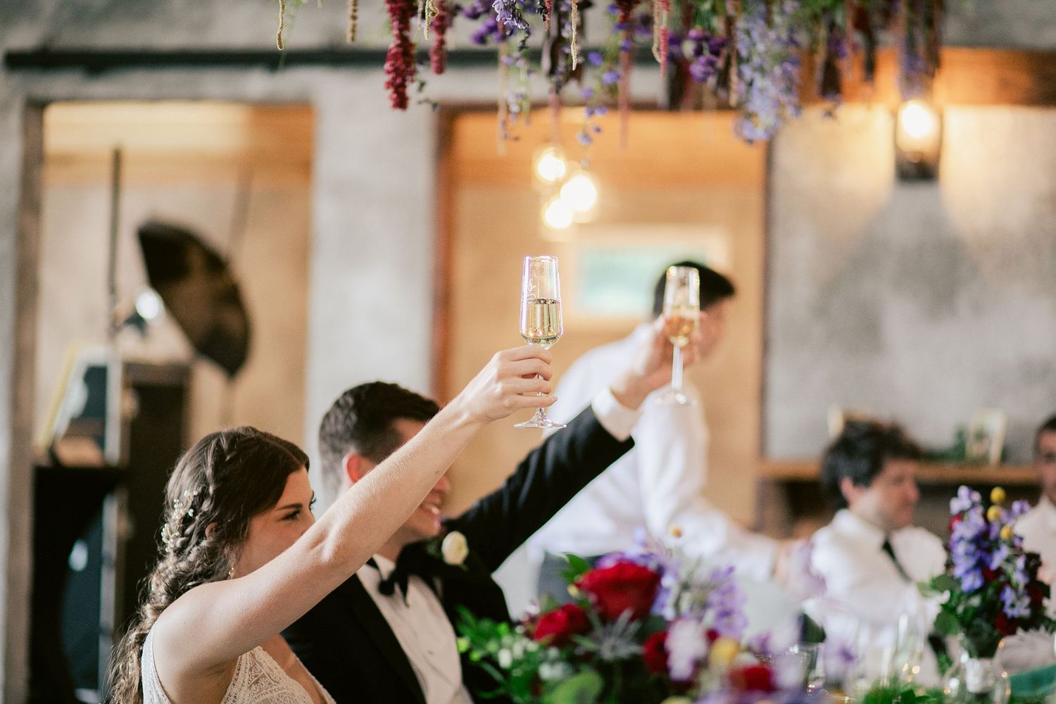 Wedding guests raise champagne glasses in a toast during reception celebration.