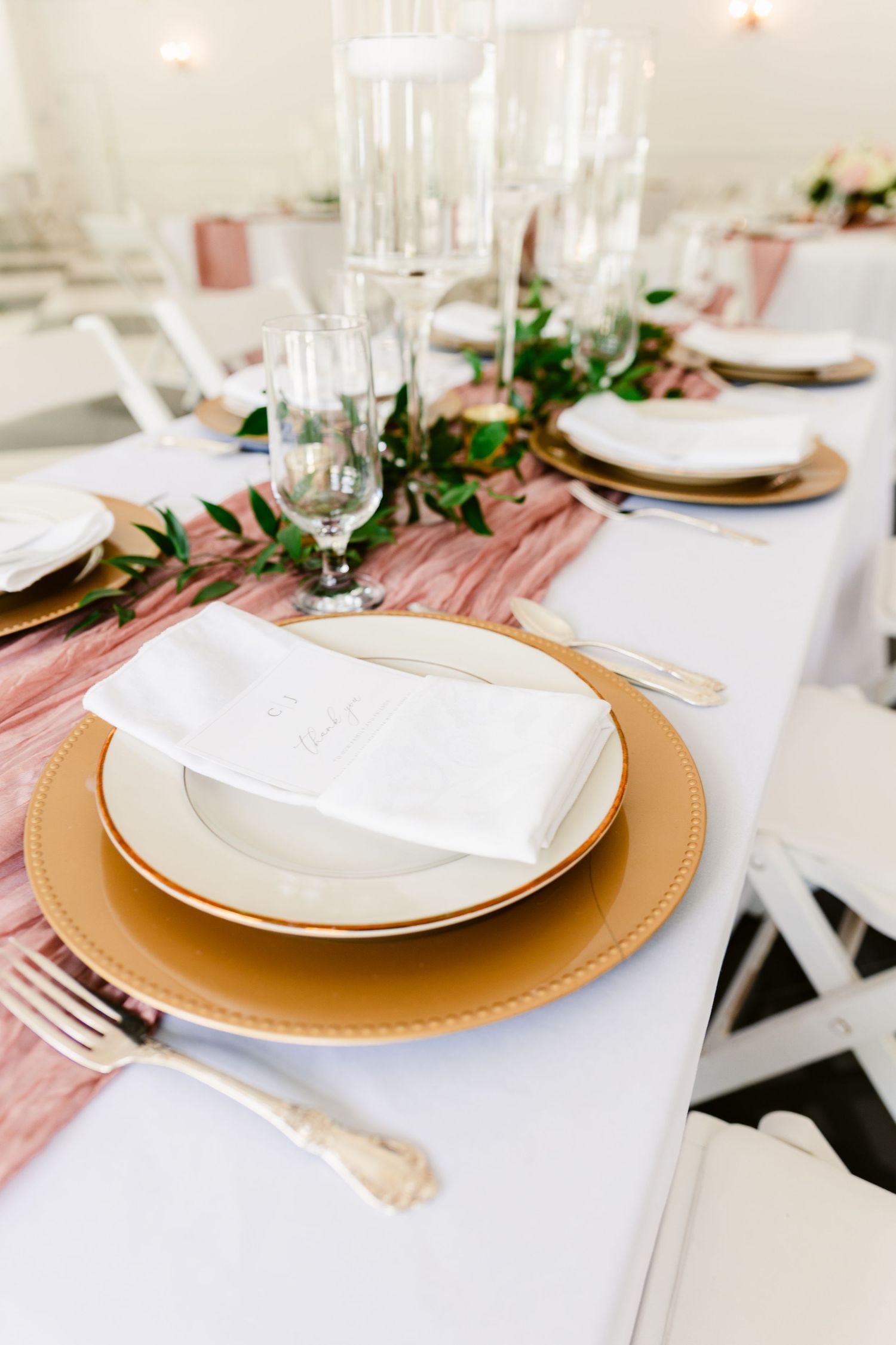 Elegant table settings with gold charger plates, white linens, and dusty rose accents.