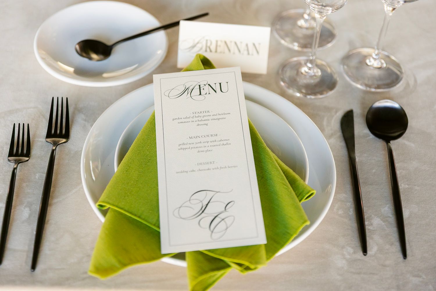 Elegant table setting with lime green napkins, wine glasses, and menu cards at a formal dining event.