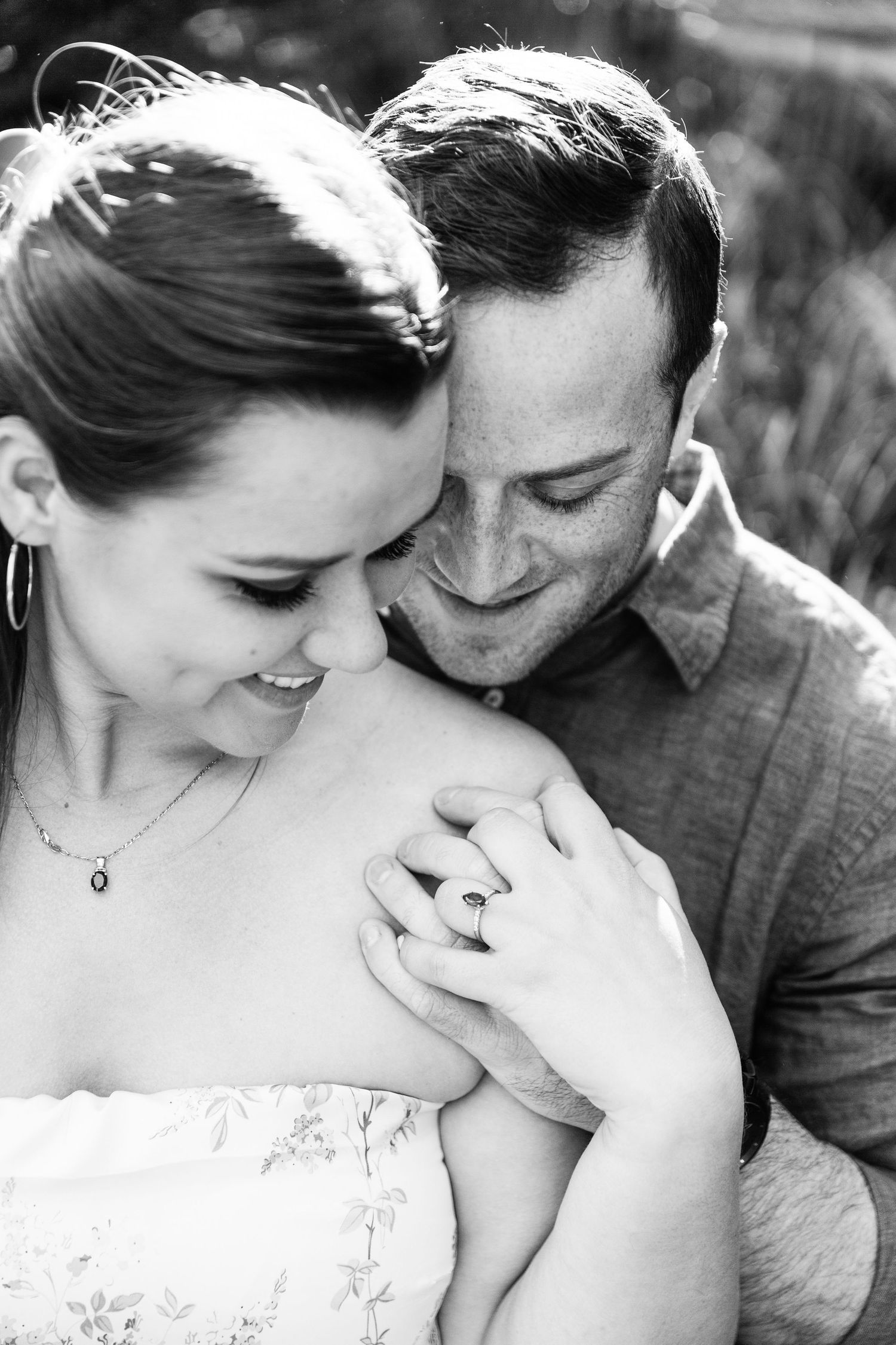 A romantic black and white portrait of a couple sharing an intimate moment together outdoors.