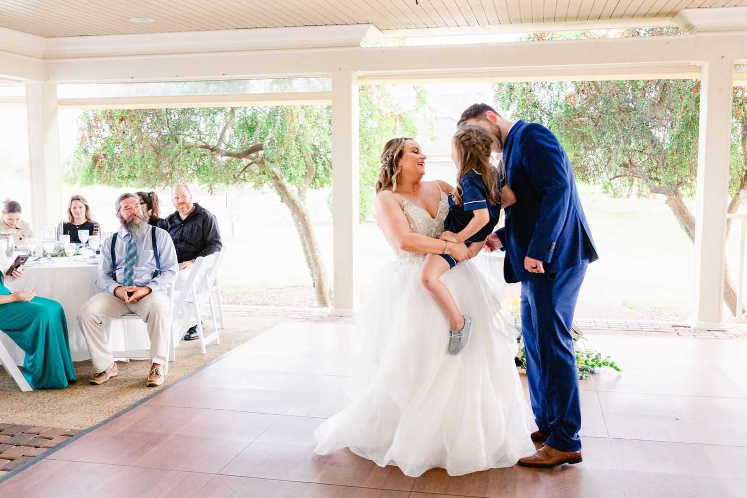 Wedding couples dancing together on a covered outdoor patio during a daytime celebration.