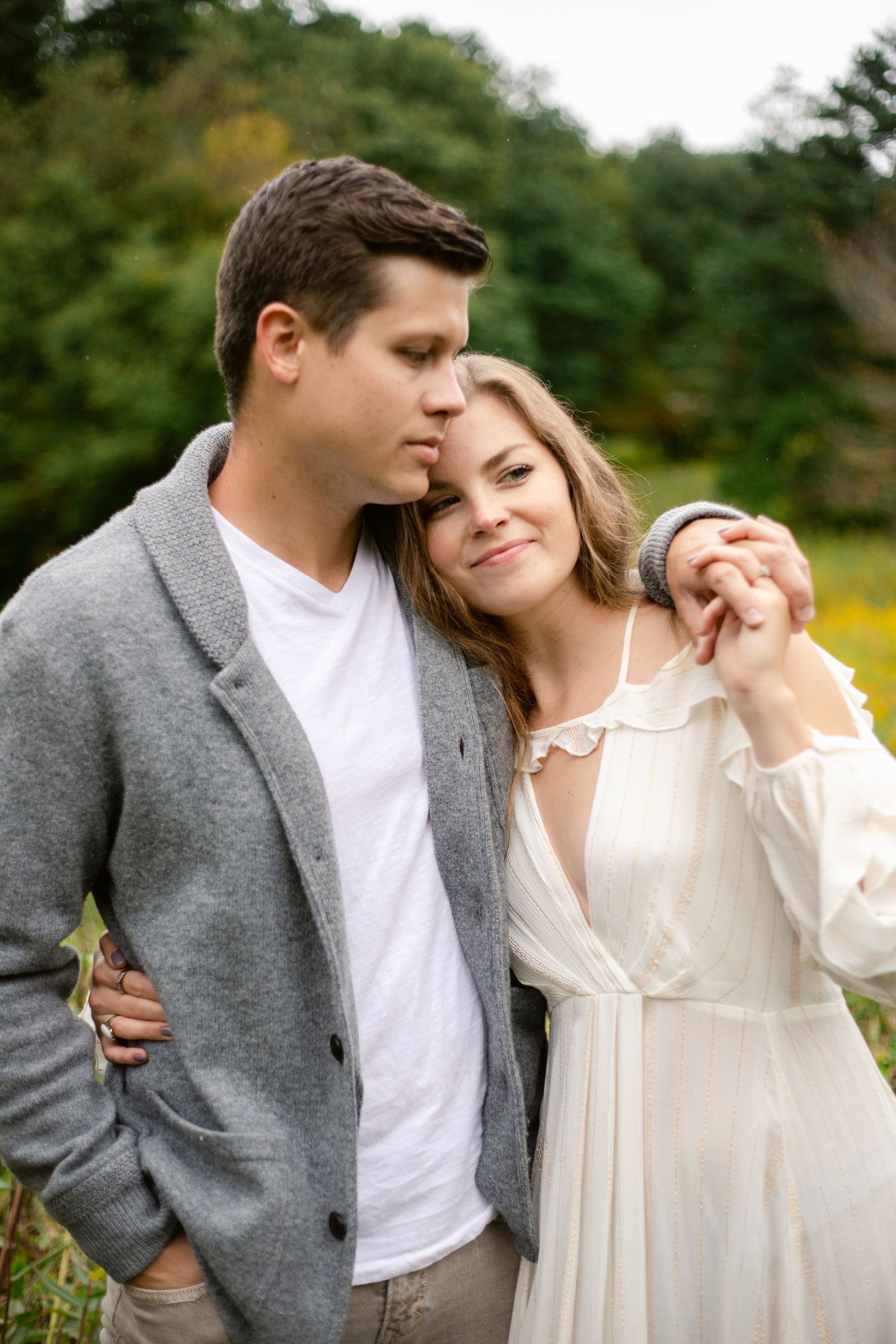 An intimate portrait of a couple embracing in casual attire against a natural backdrop.