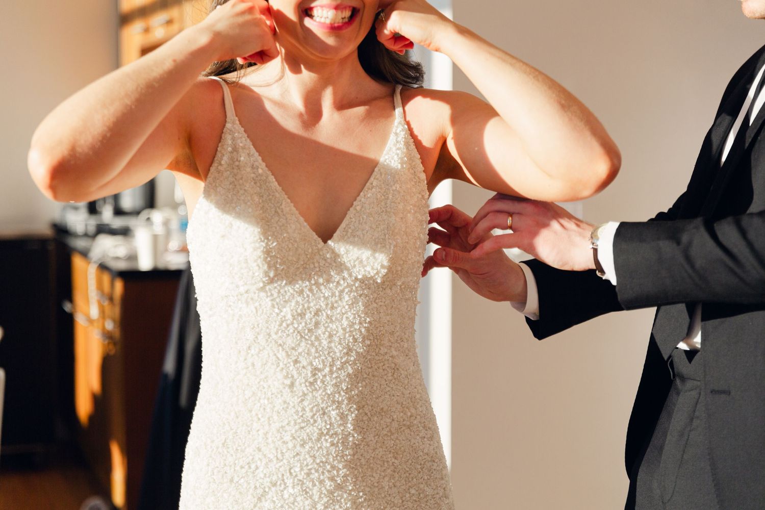 A close-up moment of a bride adjusting her wedding dress while getting ready.