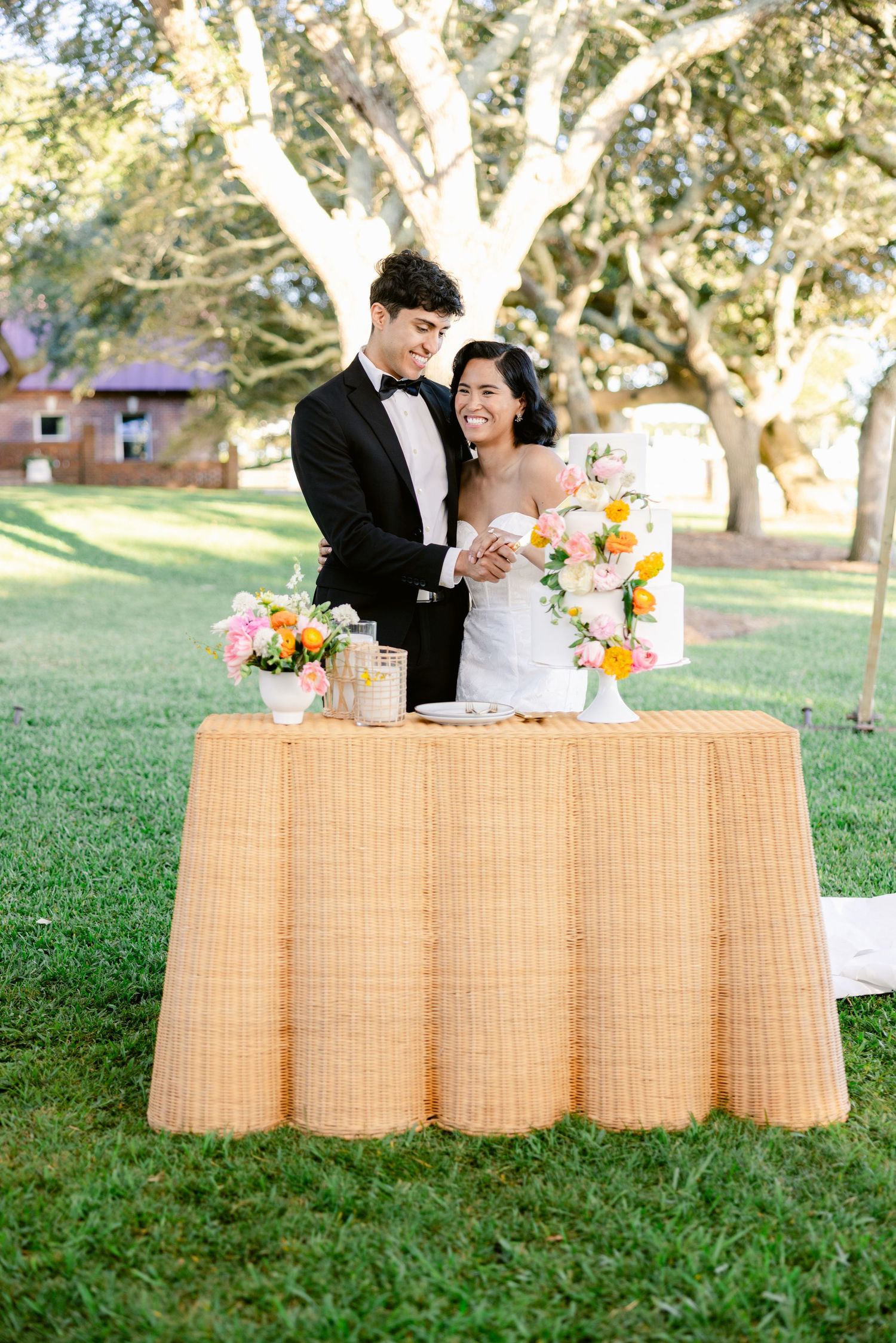 A couple shares a joyful moment at their outdoor wedding reception next to a table with floral arrangements and decor.