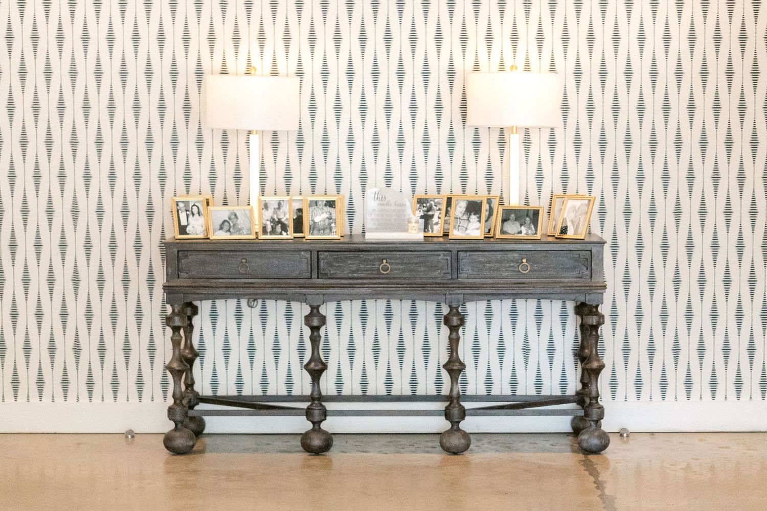 A modern interior design showroom displays elegant light fixtures and wallpaper with a geometric pattern.