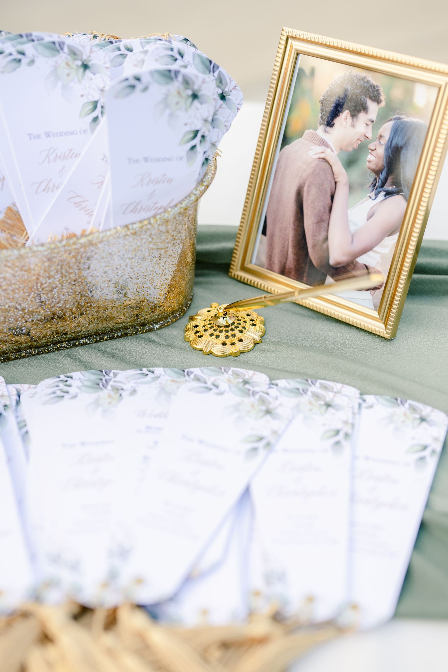 Wedding decorations display with gold-framed photos, floral accents and delicate lace details on a mint green surface.