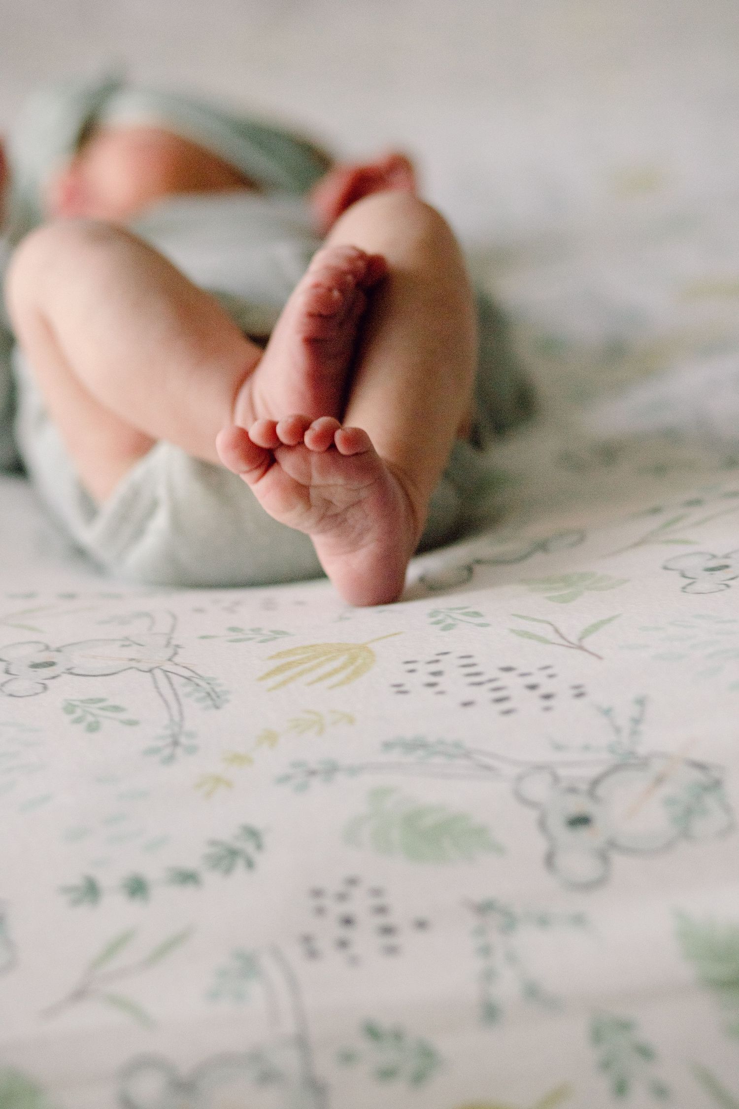 Close-up series of tiny baby feet resting on floral patterned fabric.
