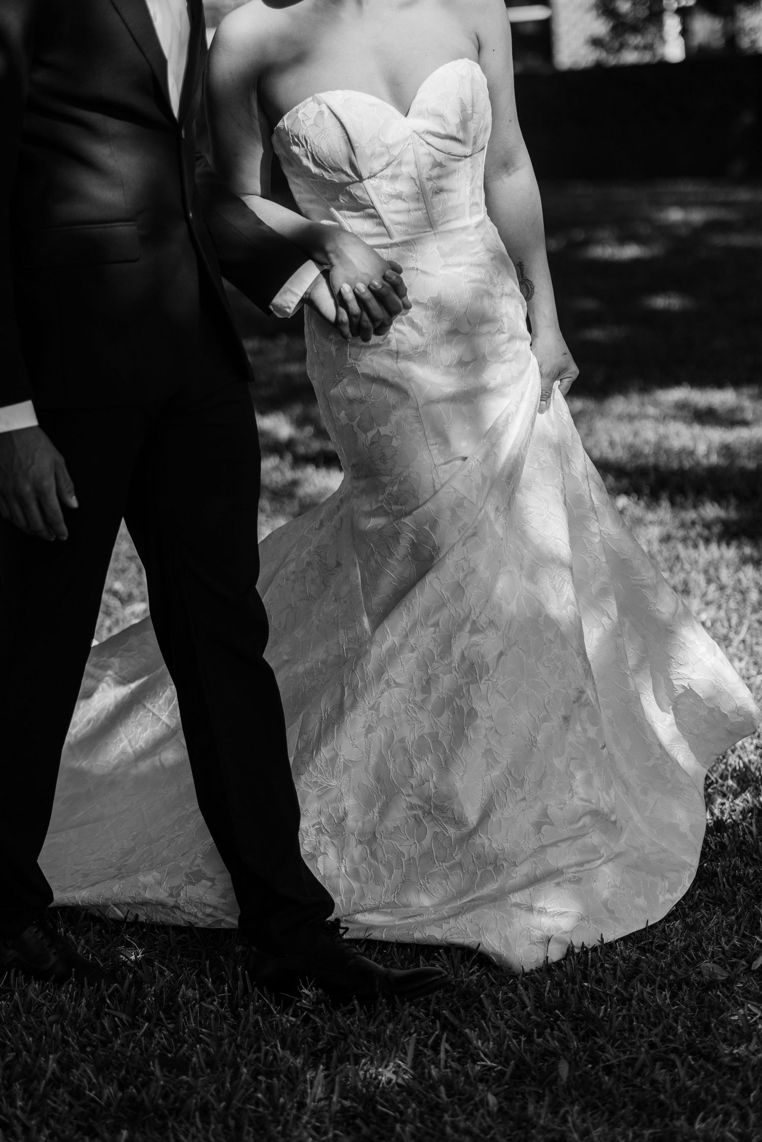 Black and white photos showing the flowing movement of a bride's wedding dress train on grass.