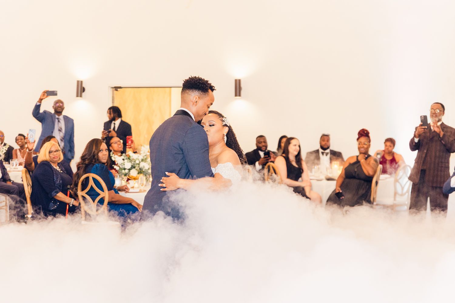 Wedding reception guests dancing and celebrating in a bright indoor venue.