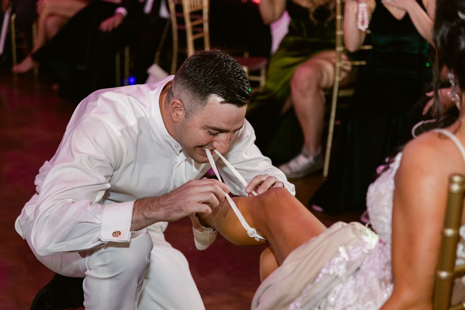 A couple shares a romantic dip and kiss on the dance floor during a wedding reception celebration.