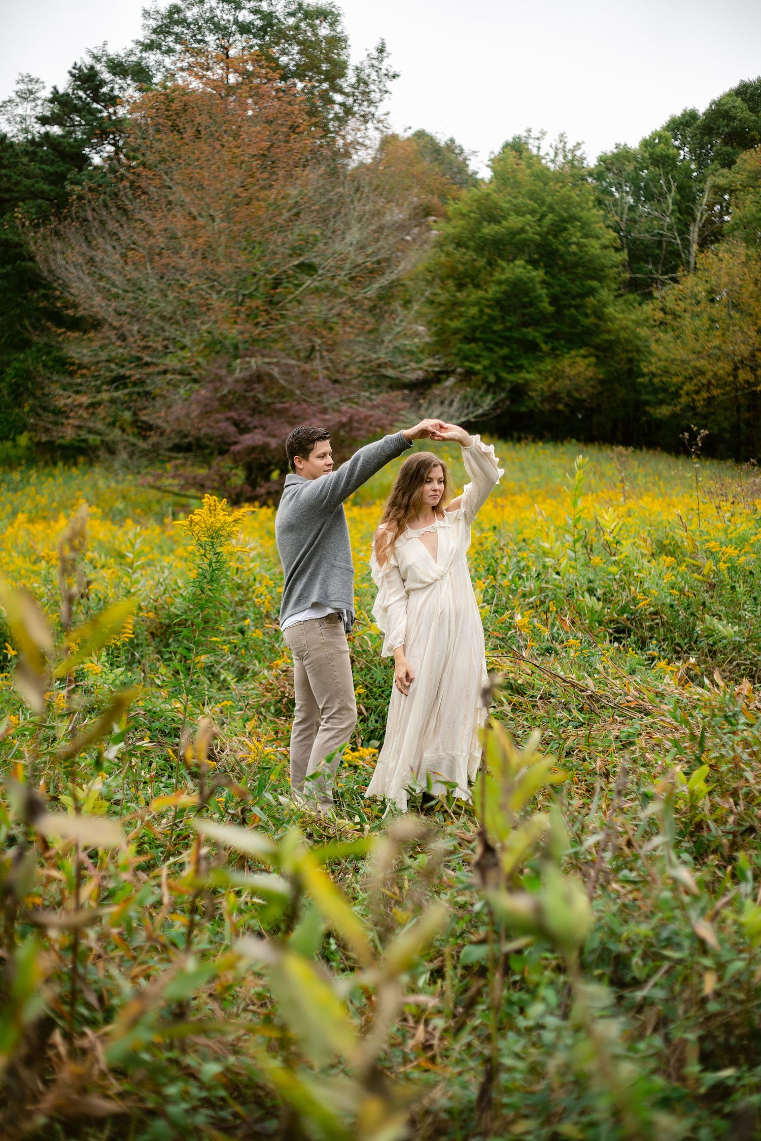 A couple dances and spins together in a field of wildflowers during golden hour.