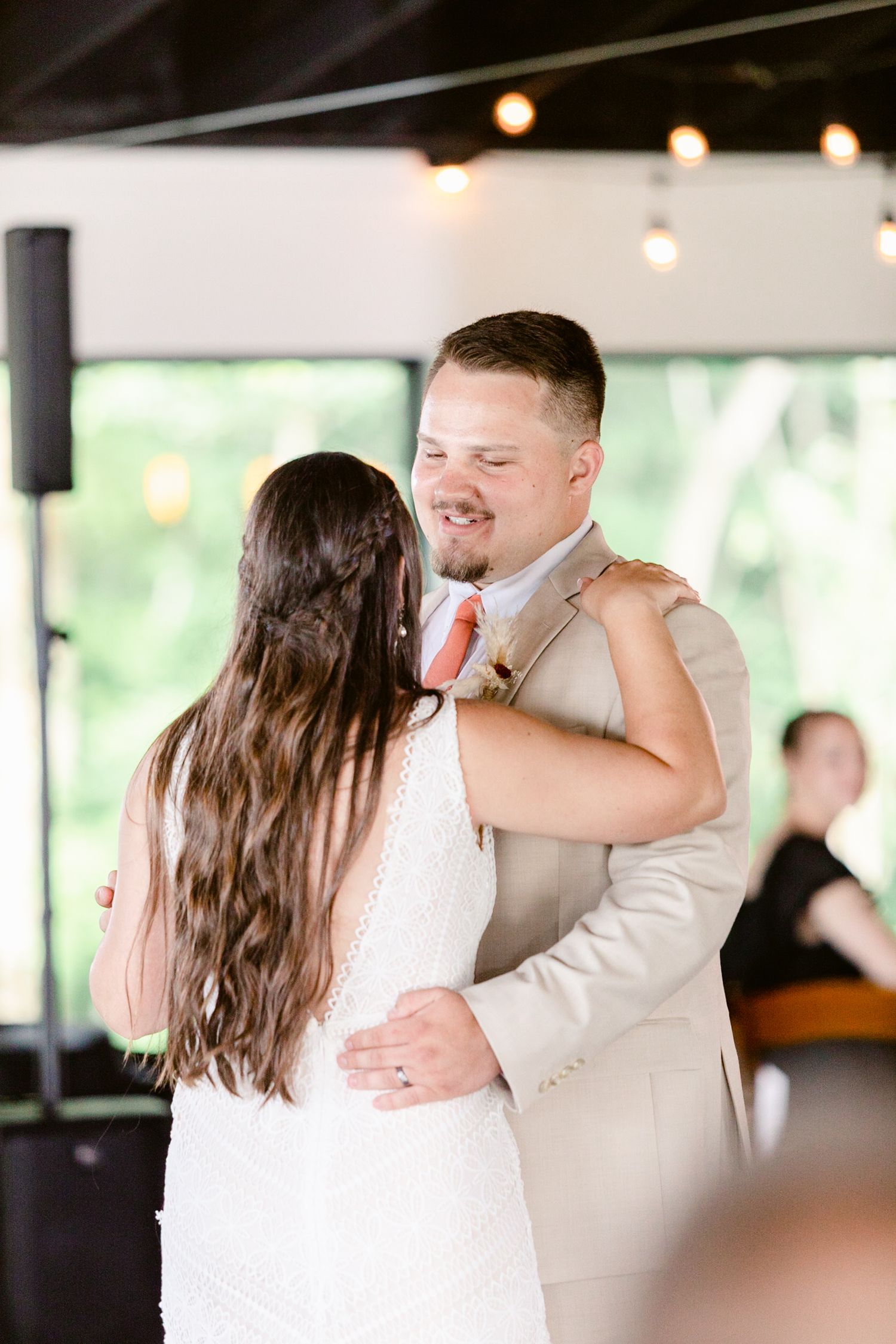 A couple shares an intimate dance moment at their wedding reception in a light-filled venue.