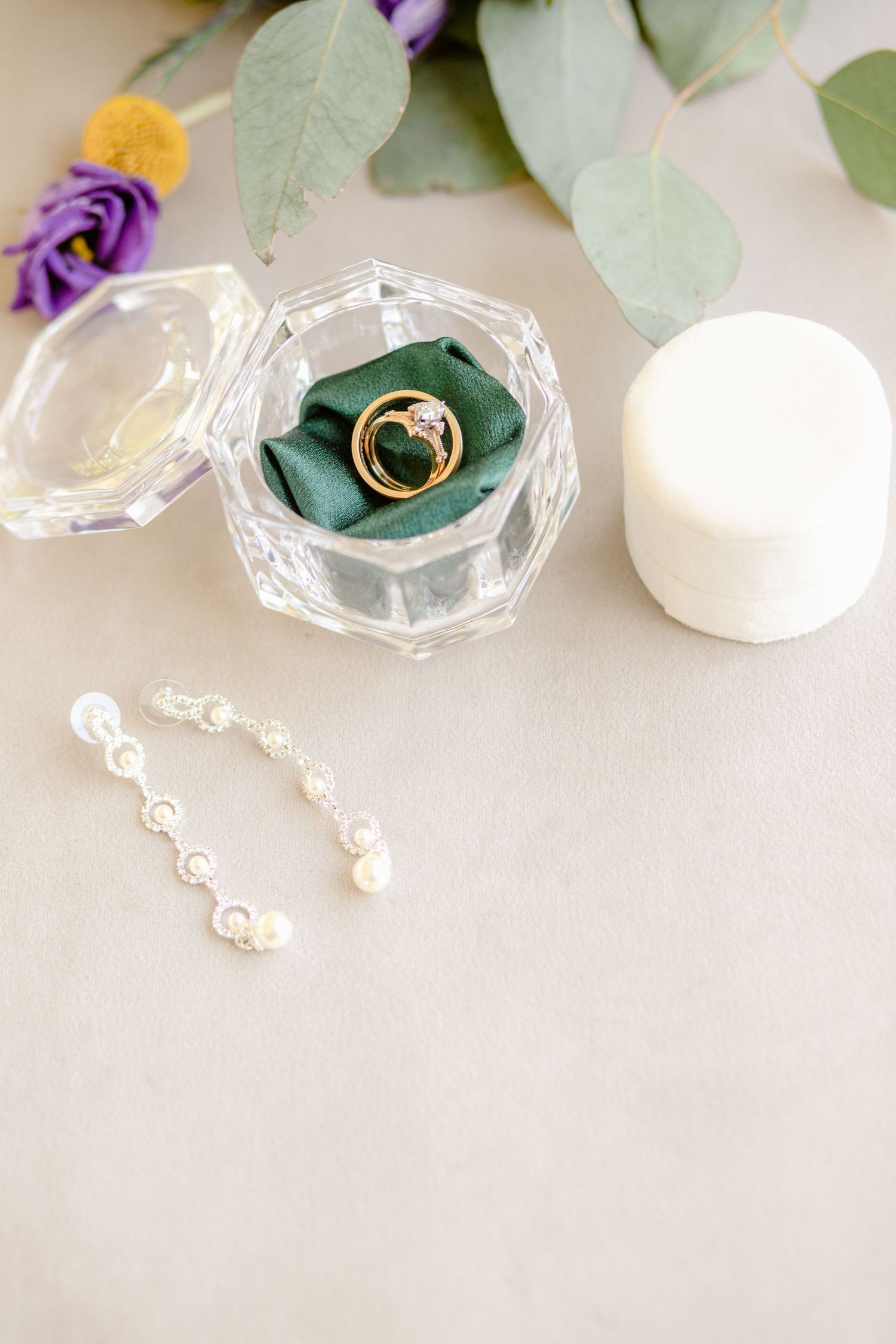 Crystal ring box with engagement ring on green velvet cushion and pearl earrings.