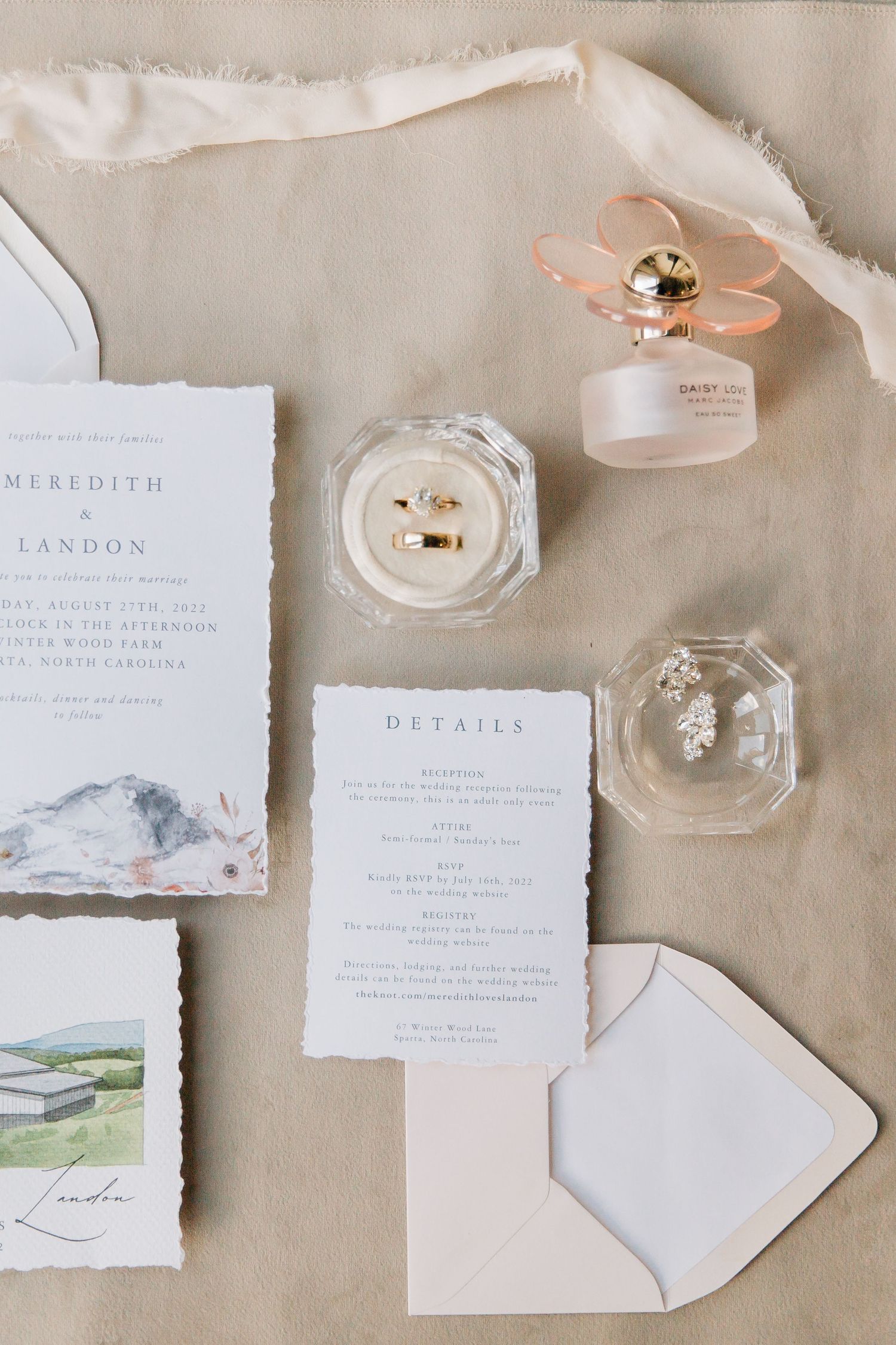 Elegant wedding stationery flat lay with rings and minimalist invitation suite.