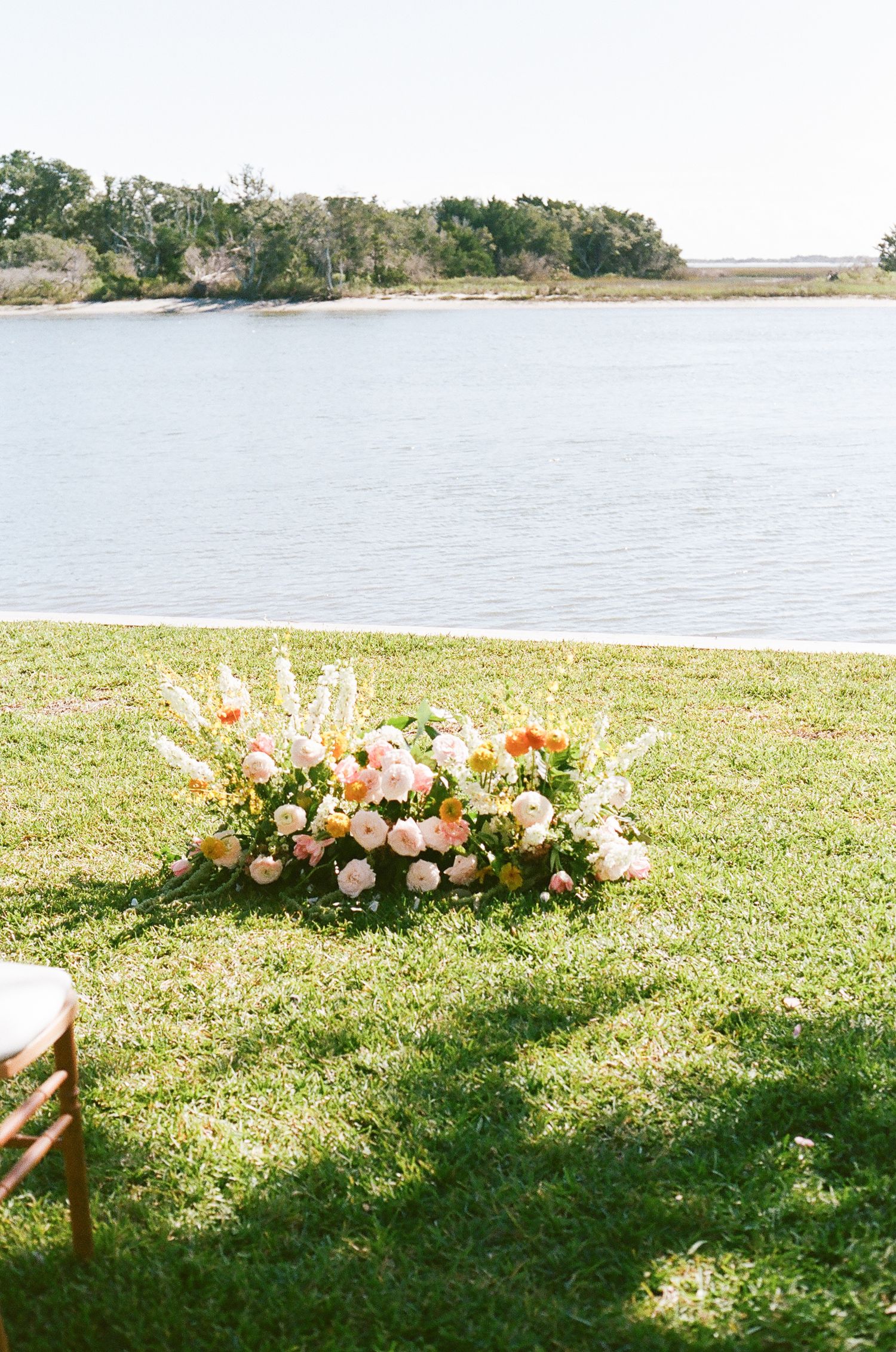 A beautiful floral arrangement with pink and peach blooms sits by a serene lakeside setting.