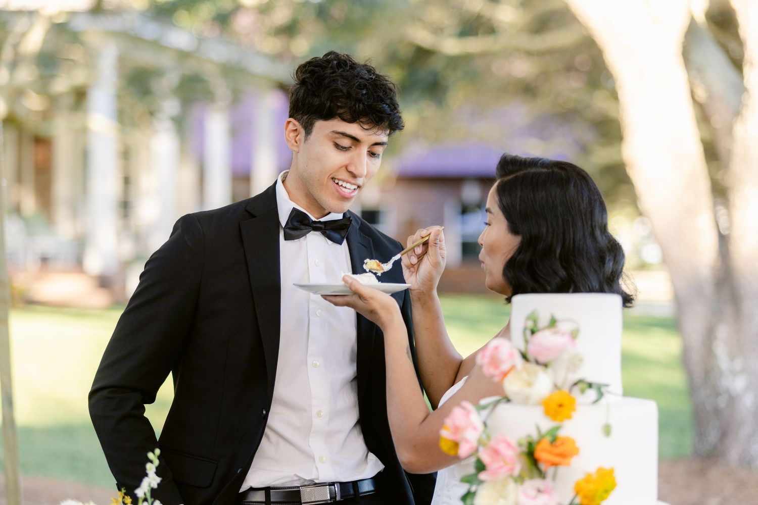 A couple shares a romantic dance outdoors at an elegant garden wedding reception with yellow floral decorations.