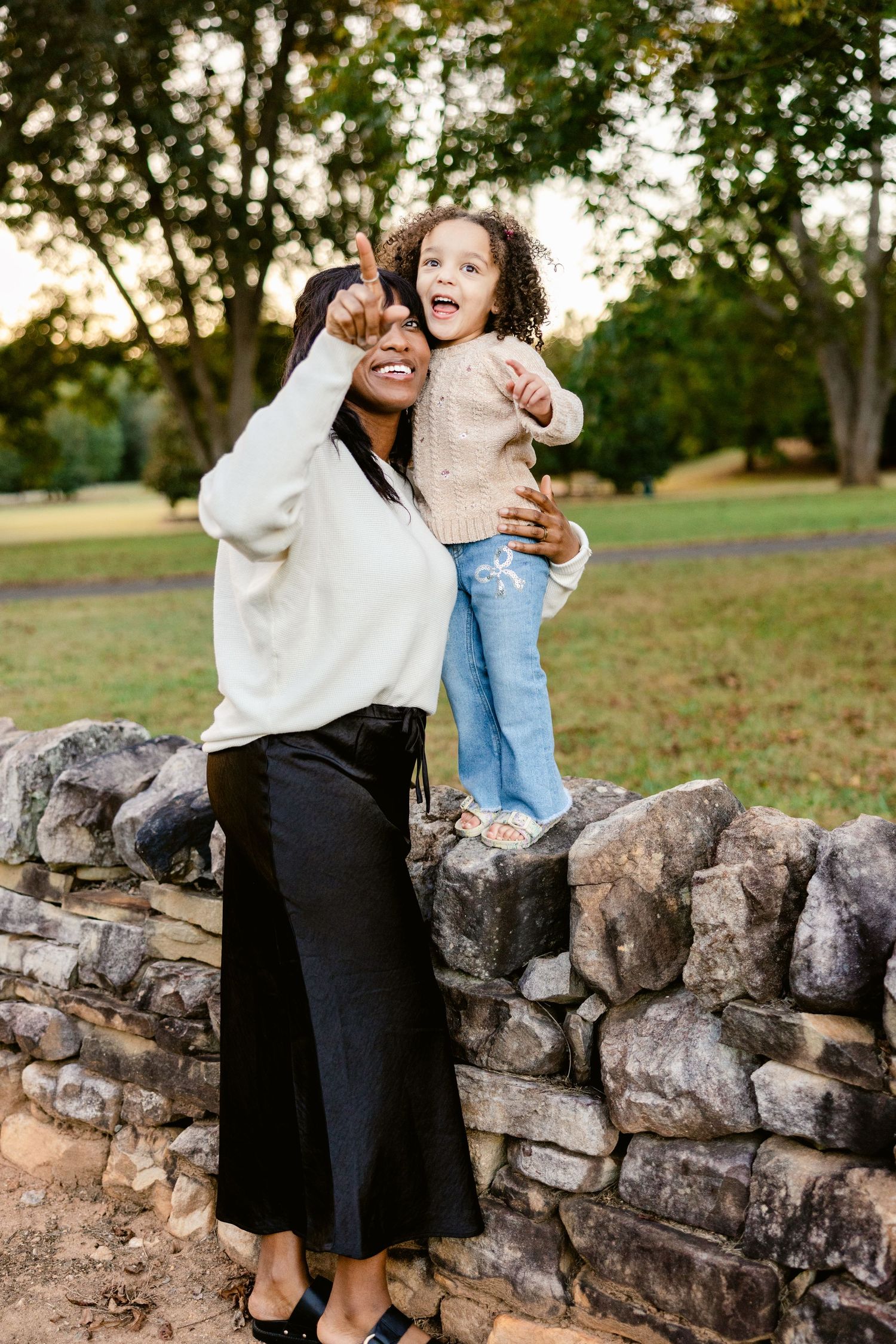 Joyful family moments captured on a stone wall during autumn outdoor photoshoot.
