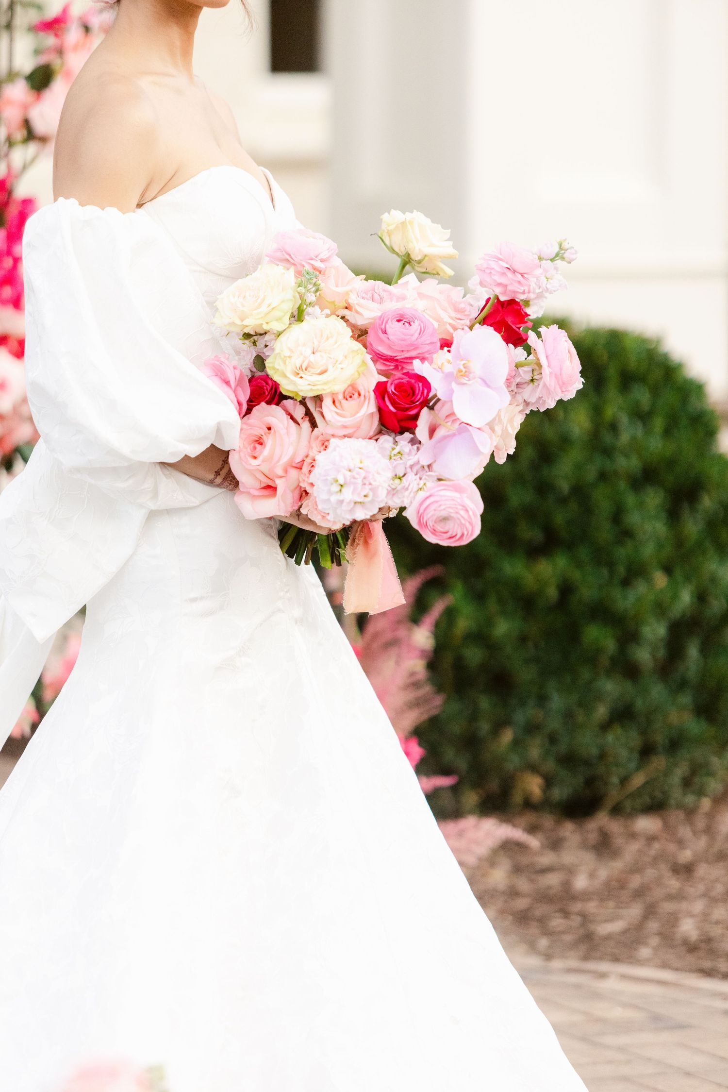 White bridal gown with pink and red floral bouquet details against a light background.