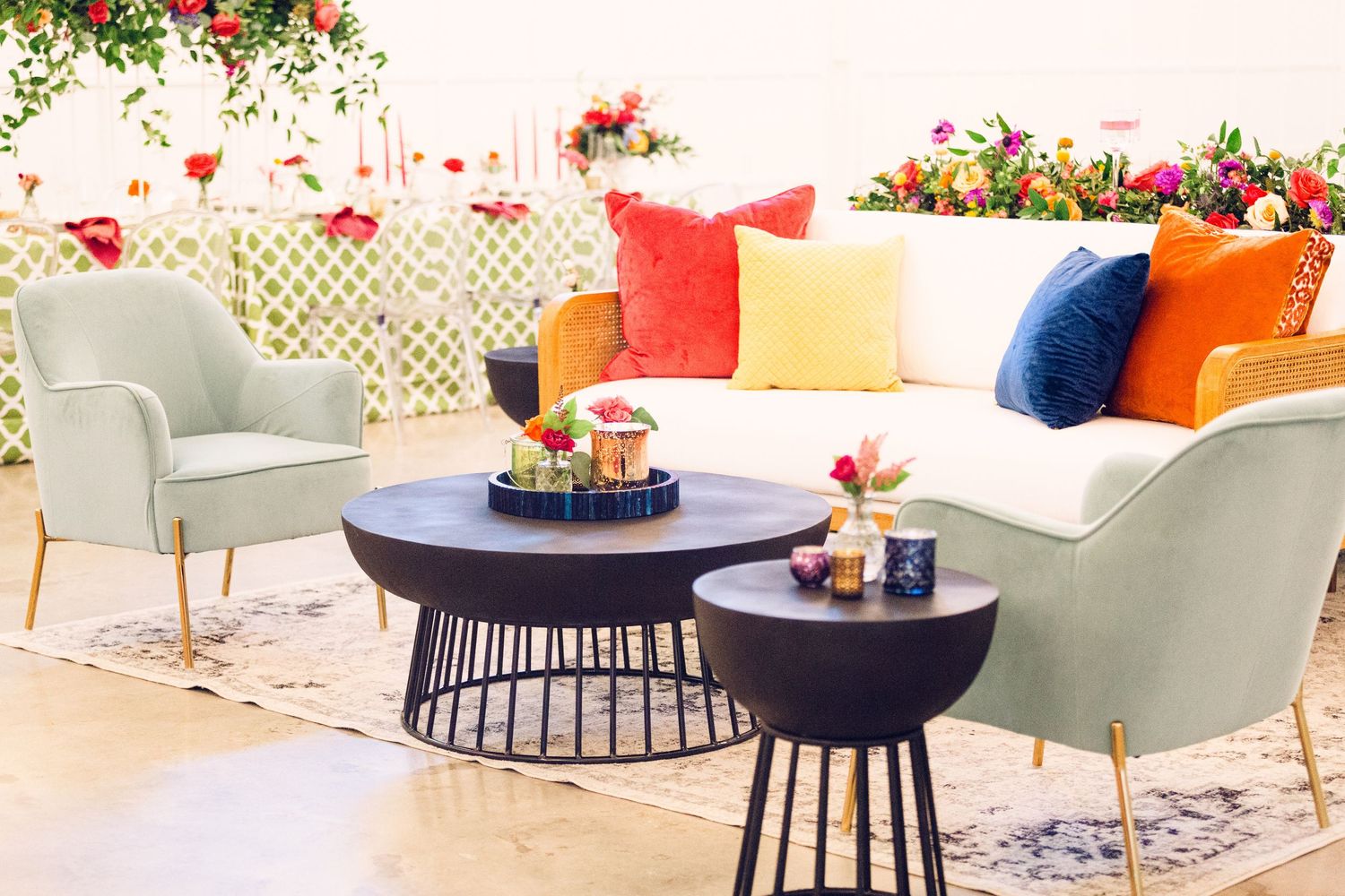 Modern outdoor patio seating with colorful throw pillows, grey accent chairs, and round black coffee tables.