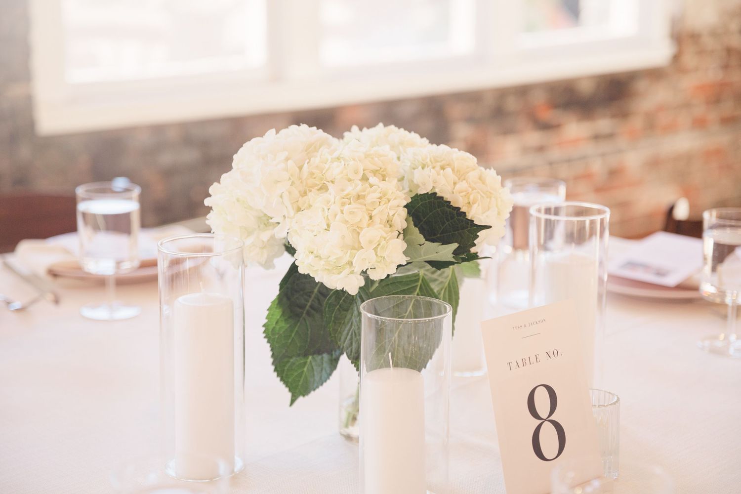 White hydrangea centerpiece with table number eight card on reception table.