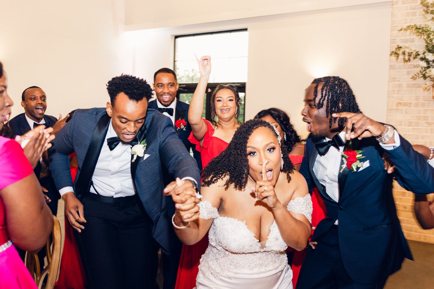 Wedding party dancing in a line at an elegant indoor reception venue.