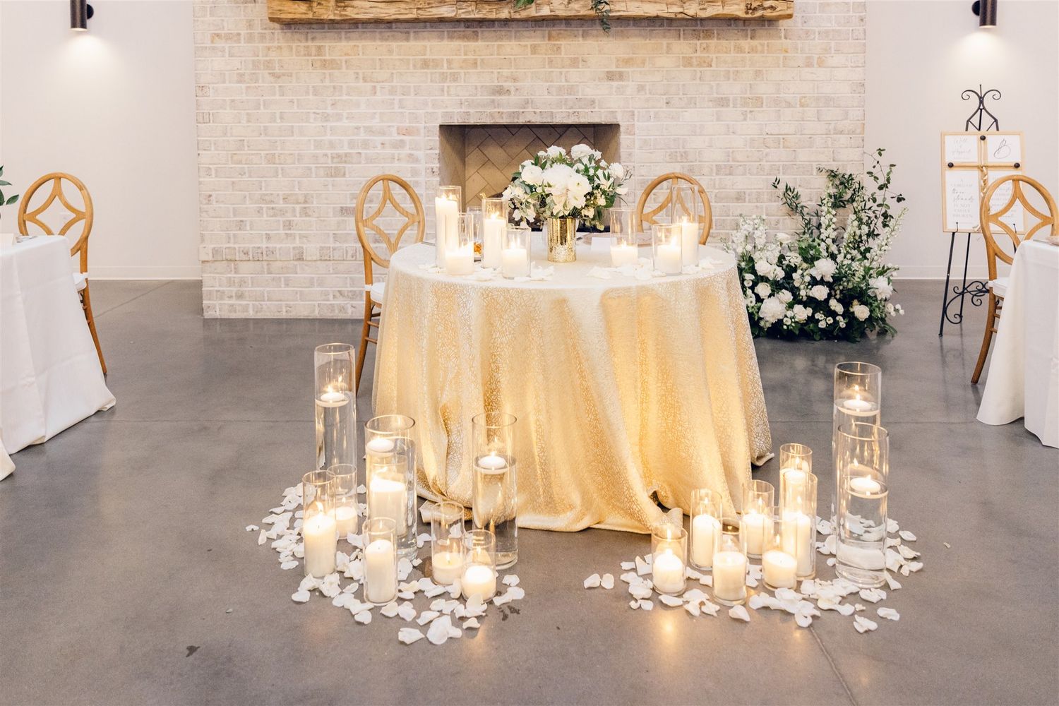 Elegant wedding reception setup with round tables draped in champagne linens and illuminated by soft glowing lanterns.