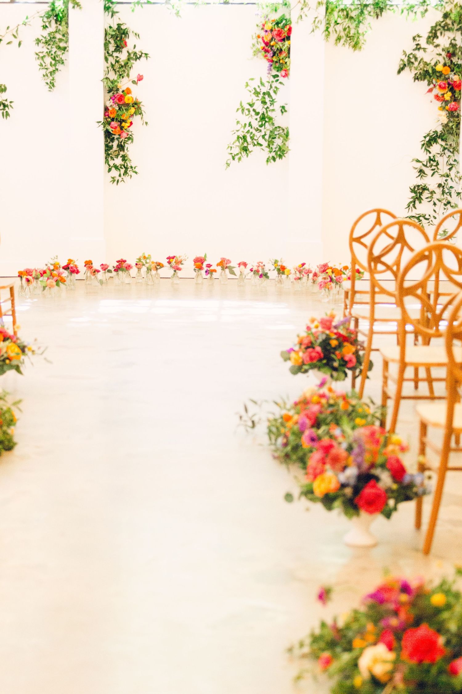 Beautiful floral arch with orange chairs and colorful roses creates an elegant wedding ceremony backdrop.