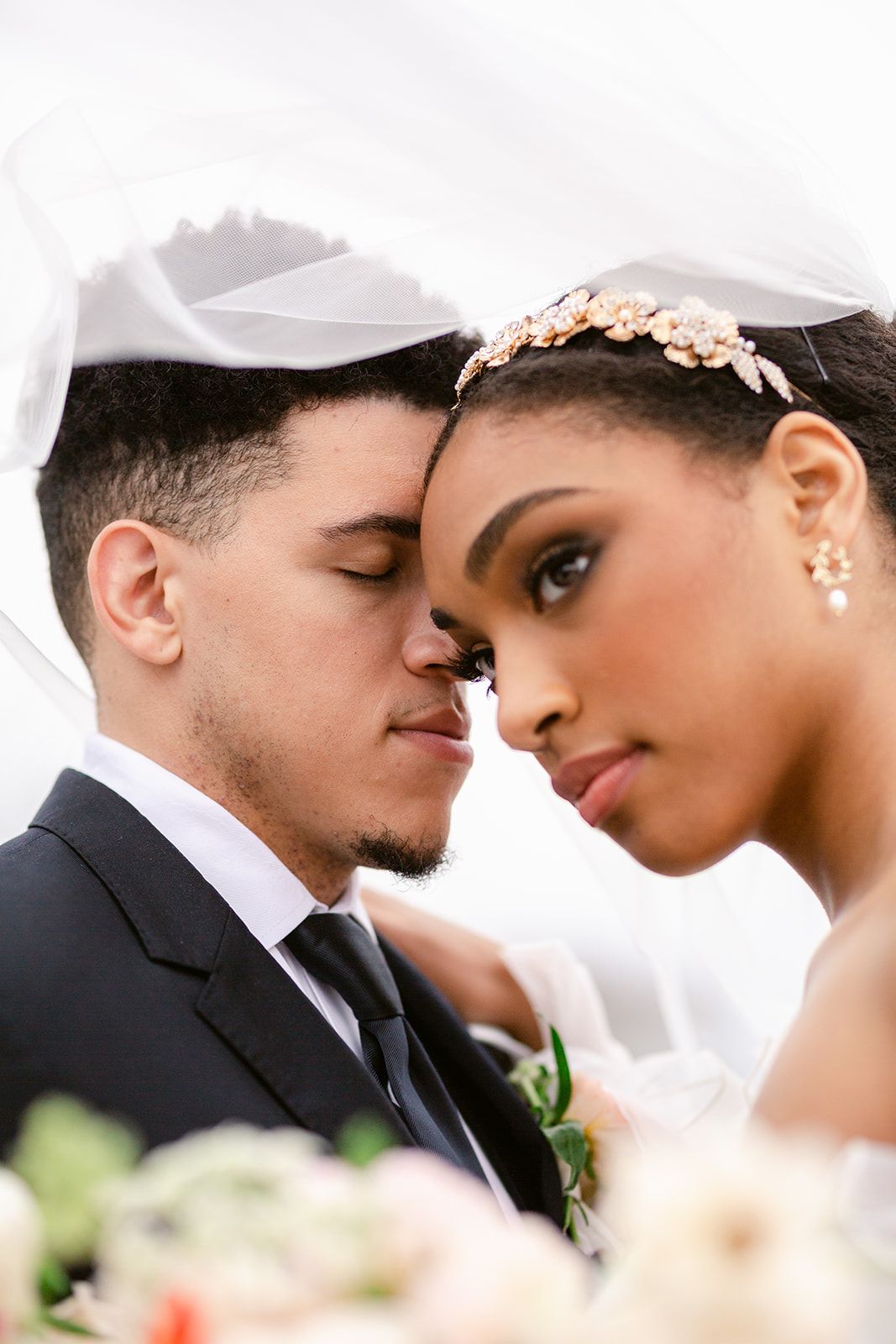 Close-up of tender wedding moment with couple in classic black and white attire.