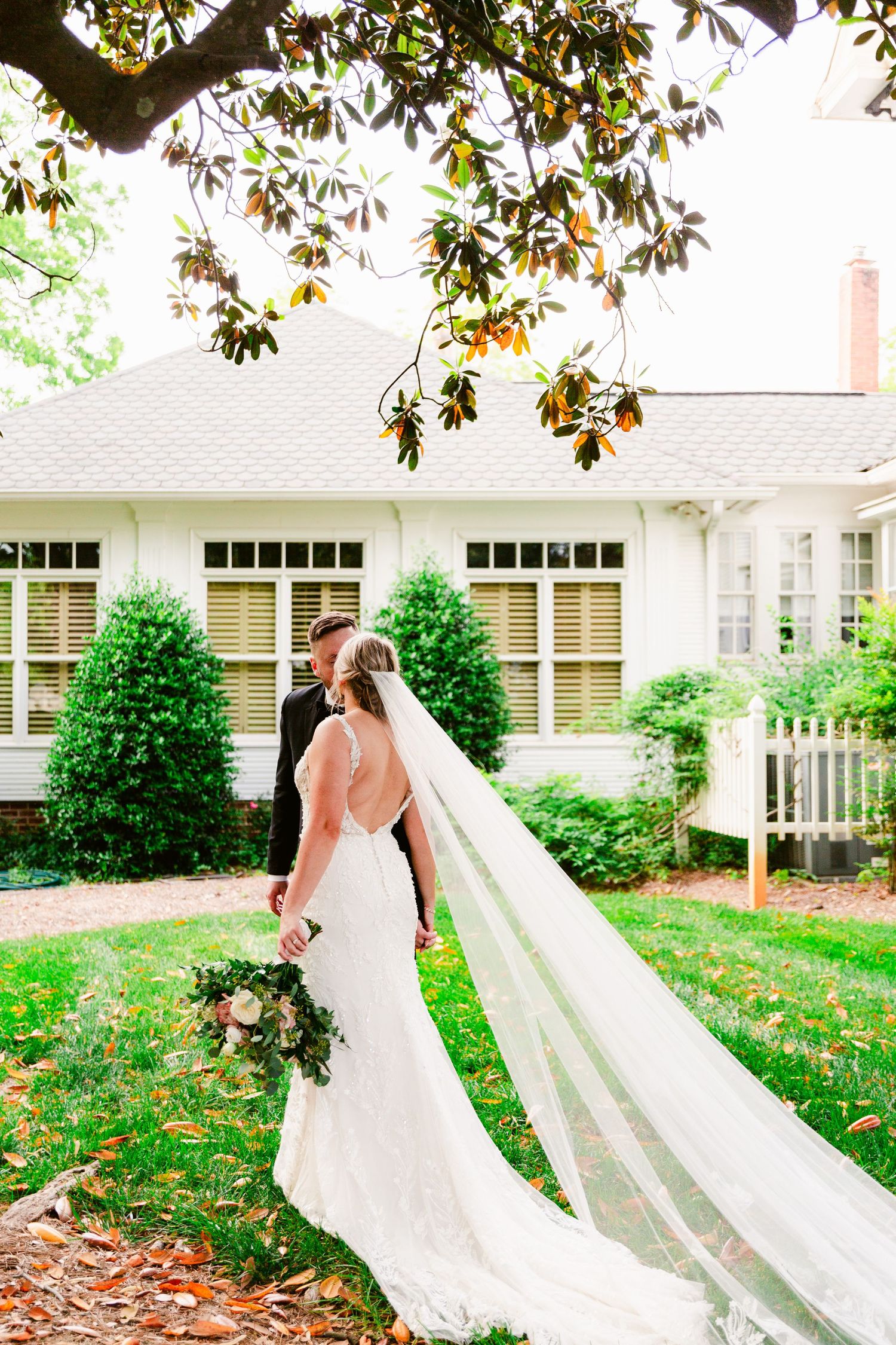 A romantic outdoor wedding photoshoot with a flowing white veil catching the sunlight under magnolia trees.