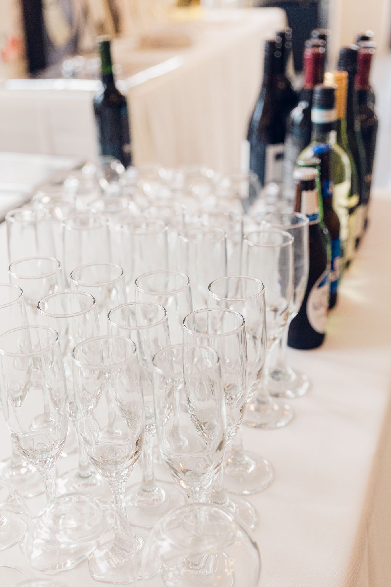 Collection of empty wine glasses and bottles arranged on a white surface for an event service.