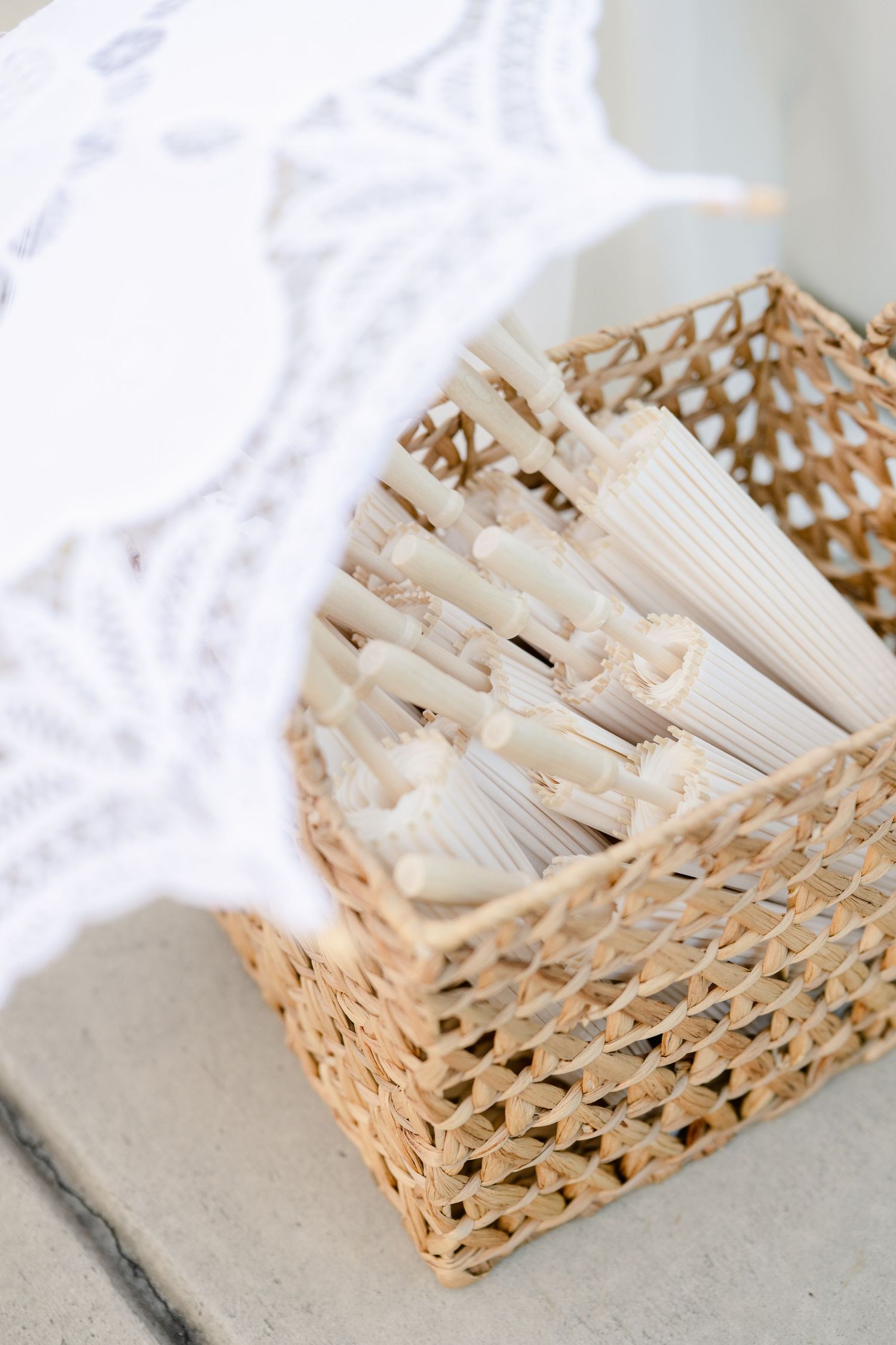 Woven bamboo basket filled with white paper napkins arranged neatly on a light gray surface.