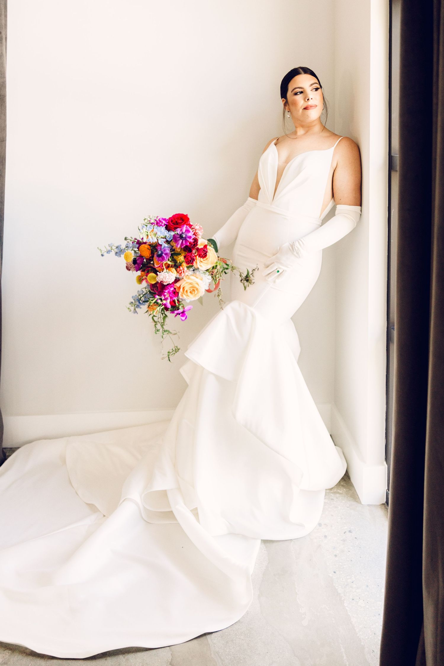 Bride in elegant white wedding gown poses with vibrant colorful bouquet against light backdrop in four sequential shots.
