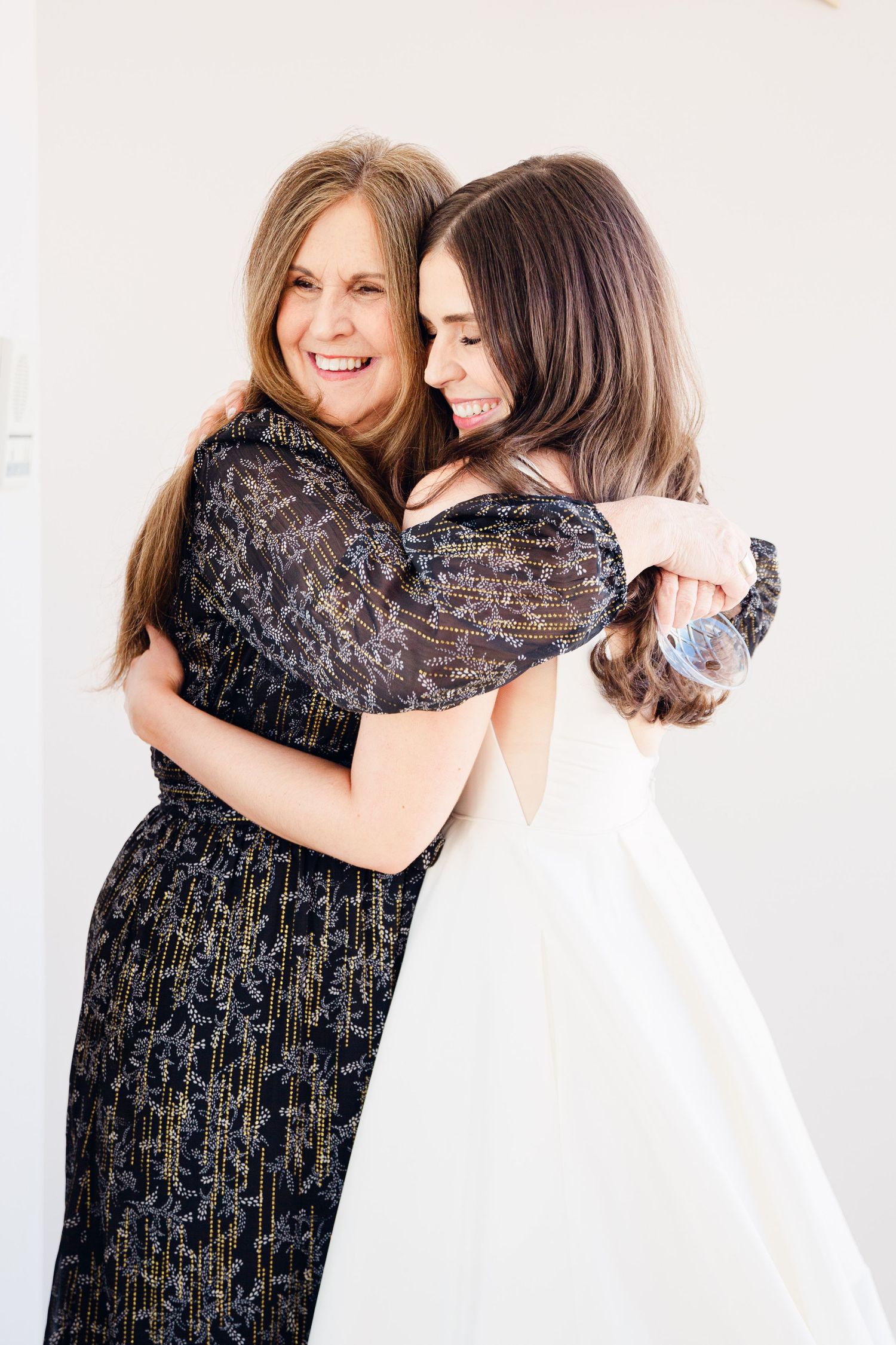 Two women embrace warmly in a series of candid black and white studio portraits.