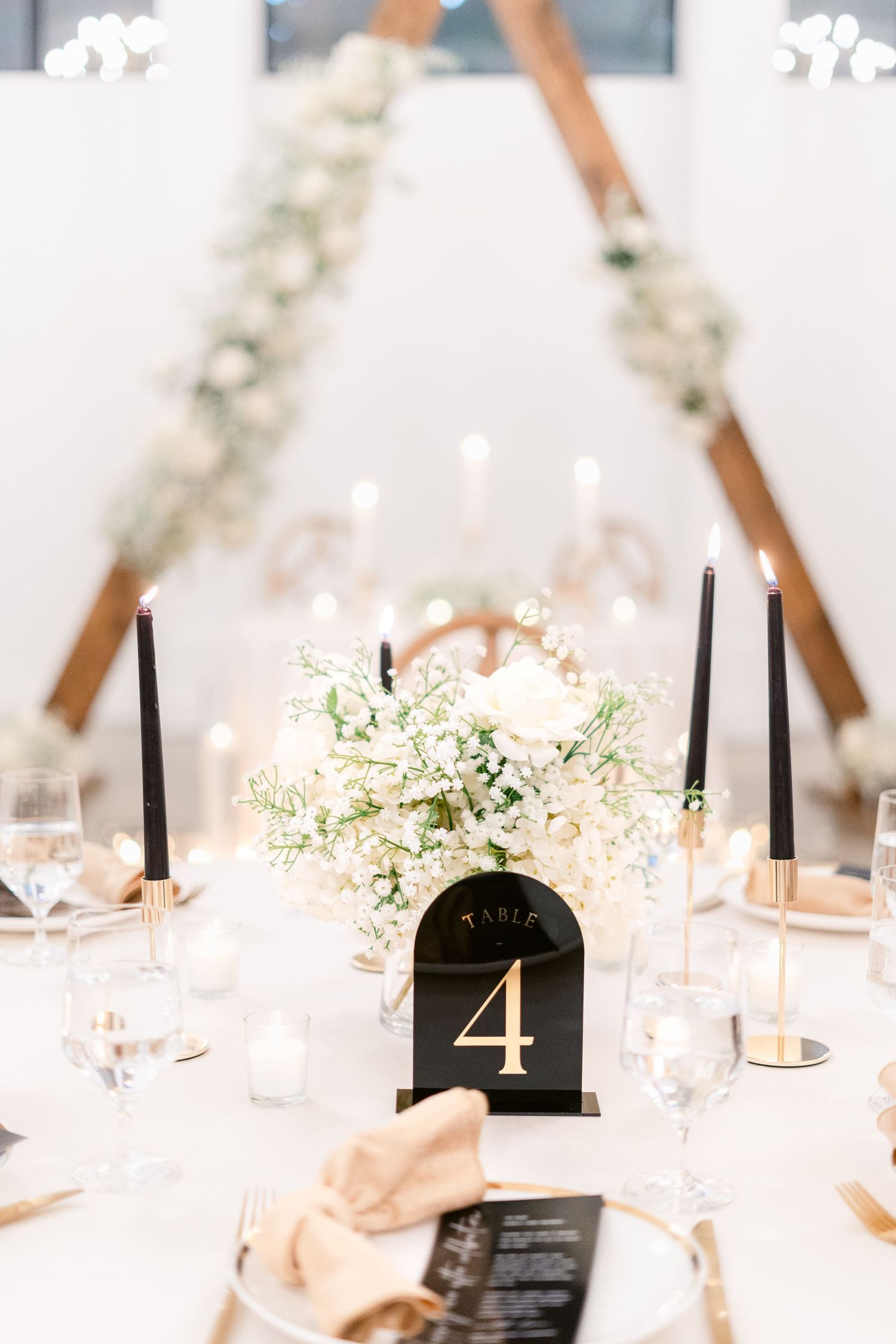 Wedding reception tables with white floral centerpieces and black table numbers.