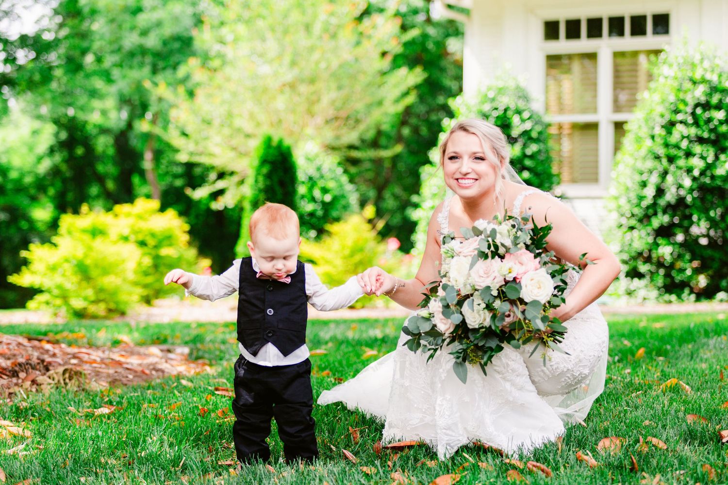 A joyful moment on a lush green lawn with white dress and formal attire against a garden backdrop.
