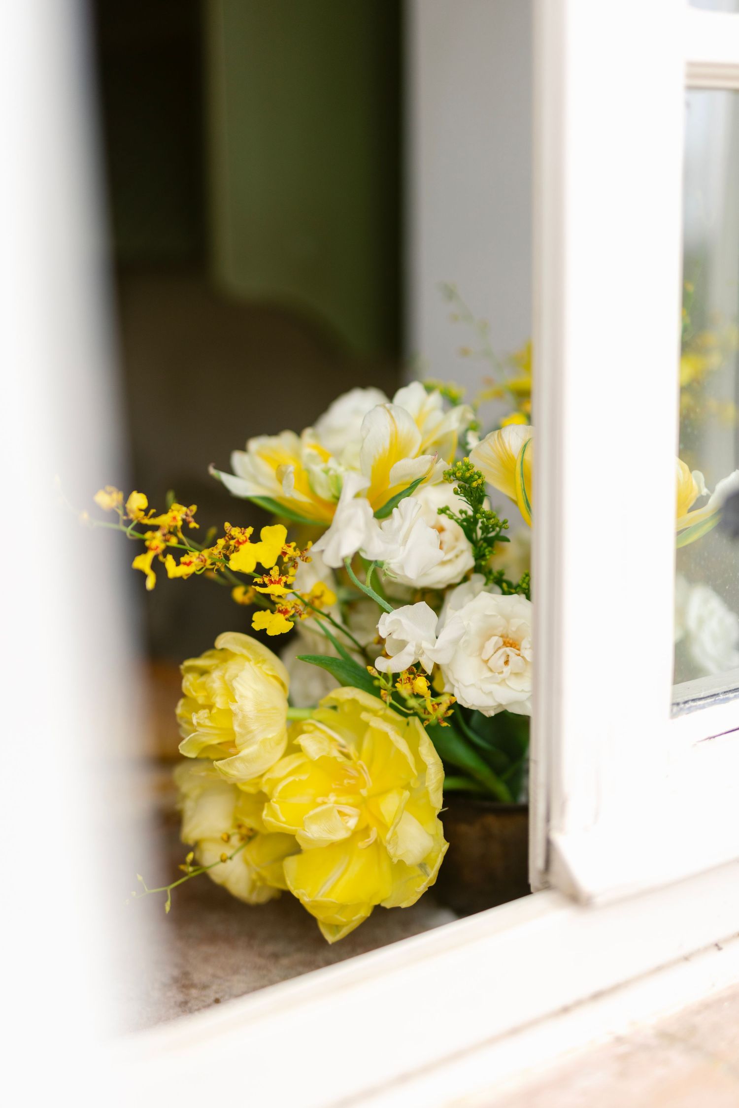 Yellow and white flowers arranged between white porch railings create a charming decorative accent.