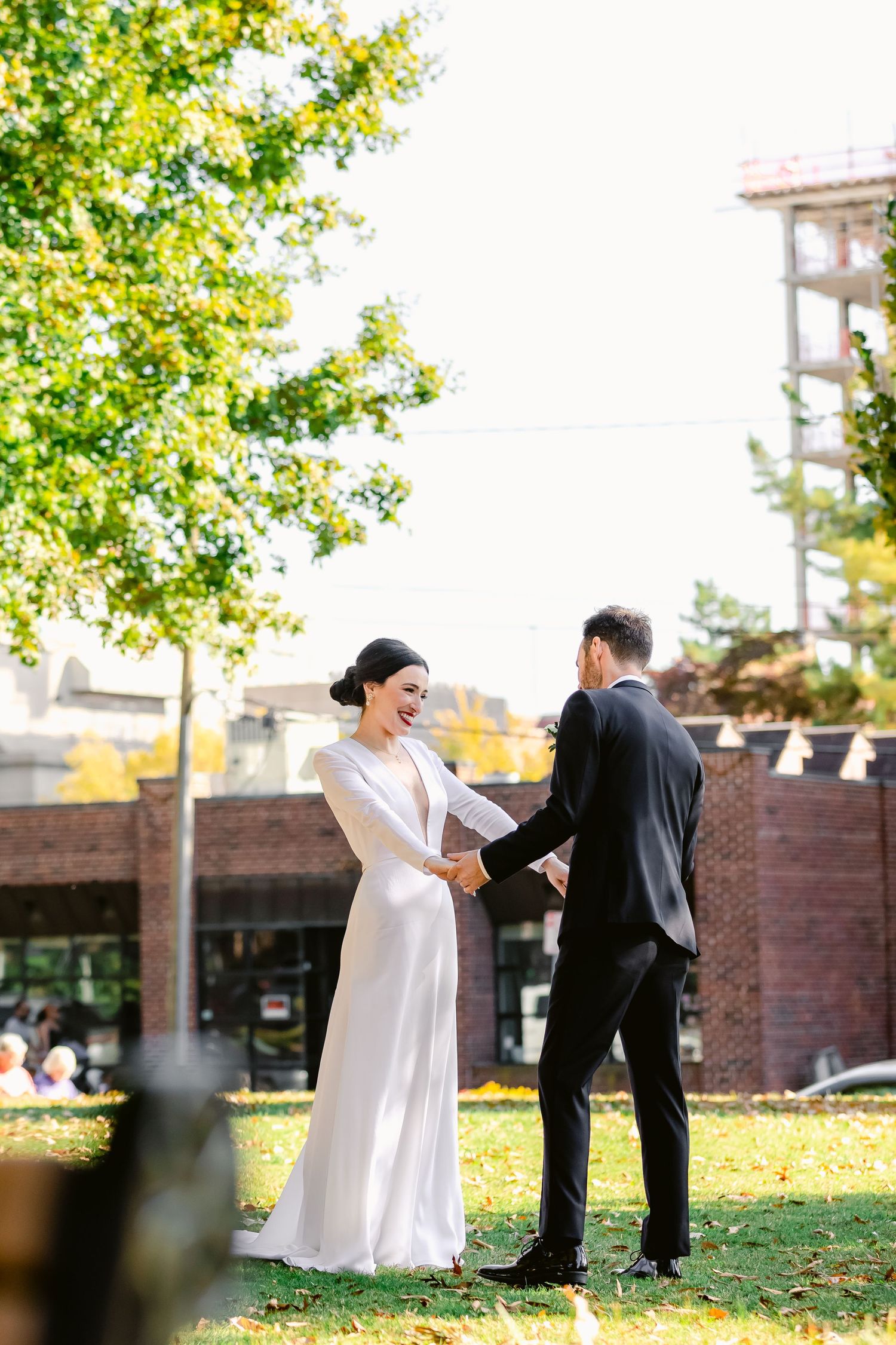 A candid wedding moment between newlyweds sharing laughter in an outdoor urban setting.
